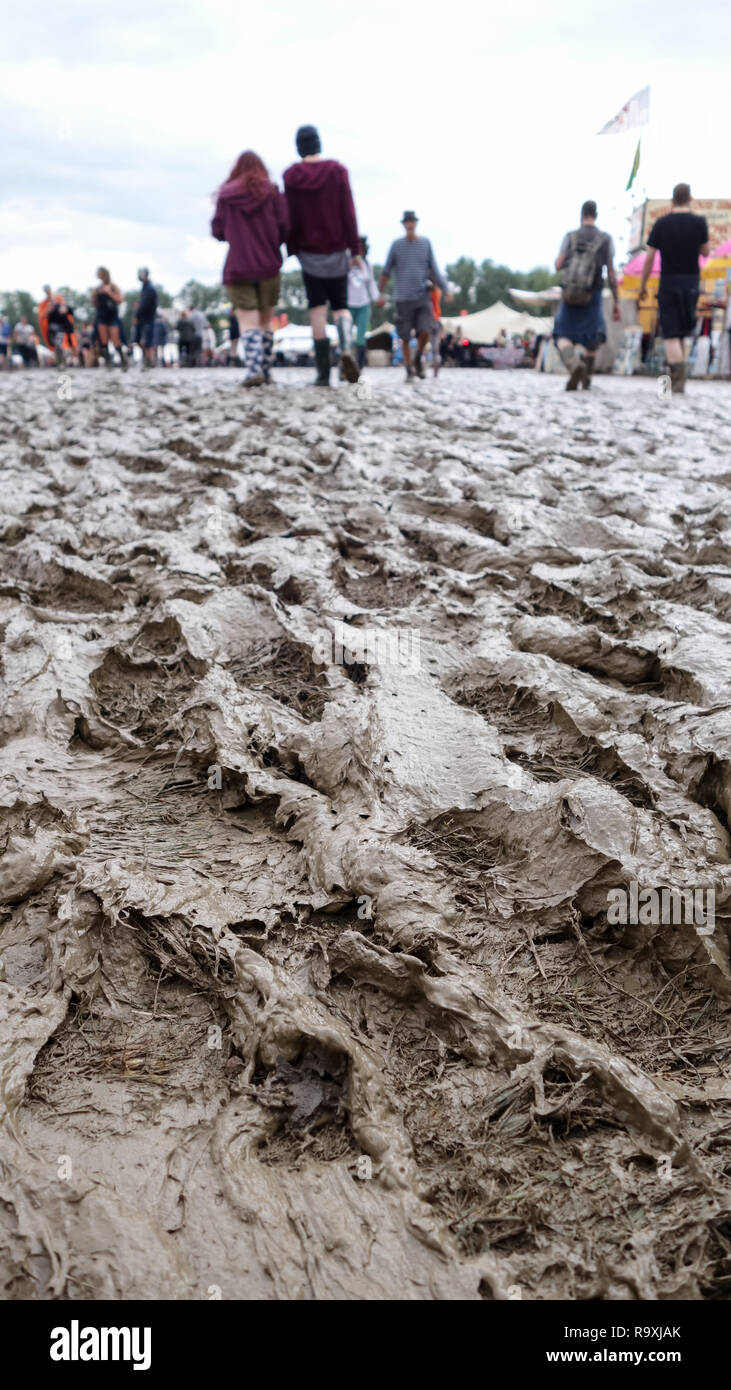 Erba girato a fango ad un festival a freddo, con persone camminare in stivali in background Foto Stock