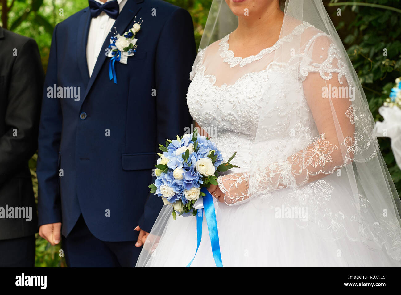 Bellissima bridal bouquet di rose e ortensie sullo sfondo sposa e lo sposo stand ad una cerimonia di nozze Foto Stock