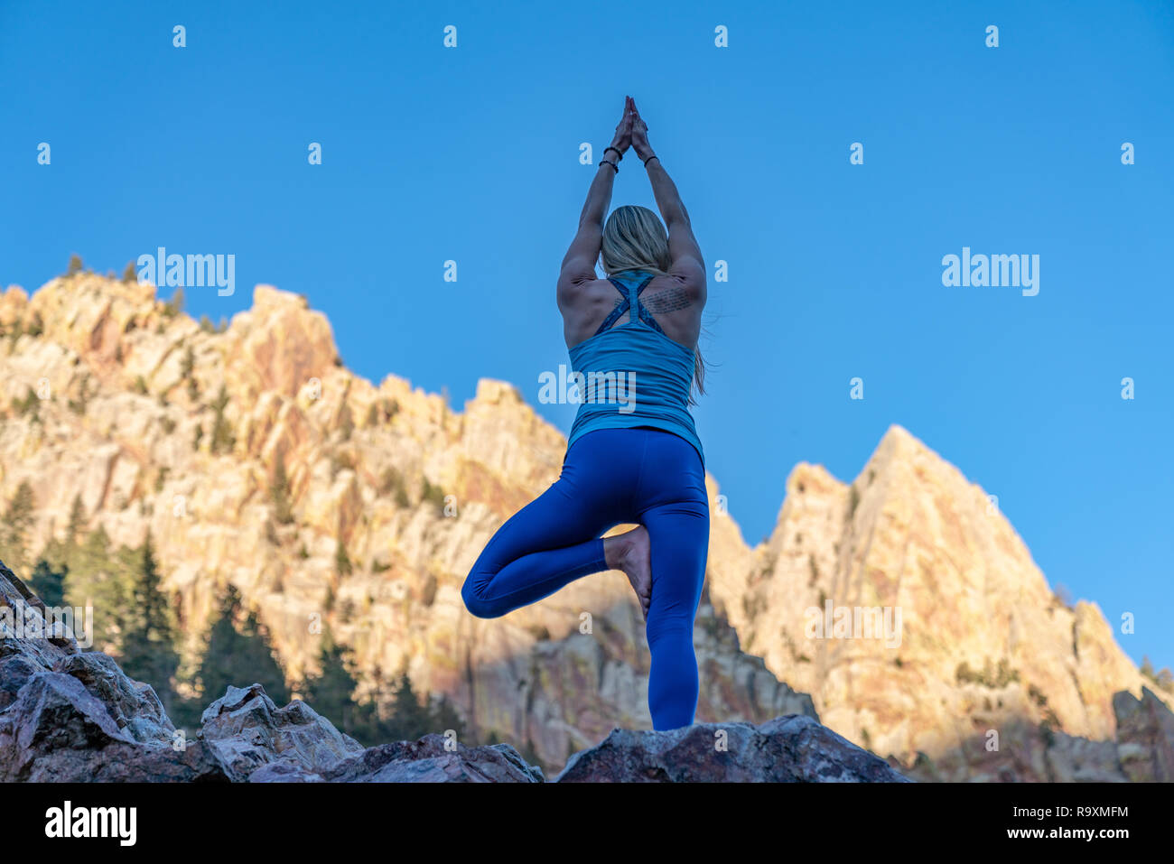 Donna fare yoga all'esterno la posizione dell'albero e Guerriero 3 Foto Stock