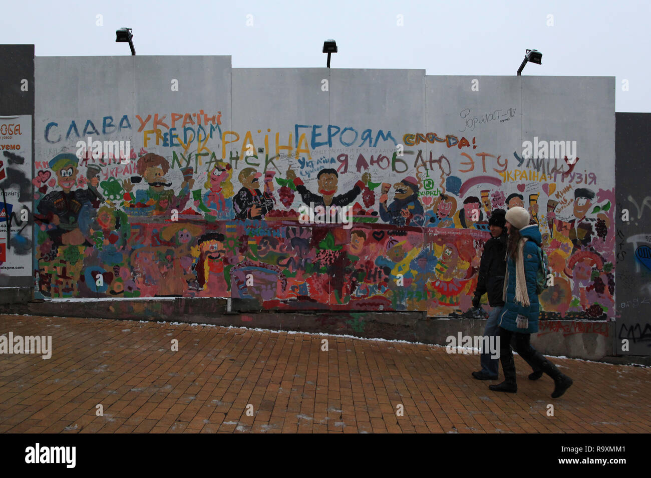 Una giovane coppia passa una pittura murale durante la camminata fino la discesa Andriyivskyy. Kiev, Ucraina. Foto Stock