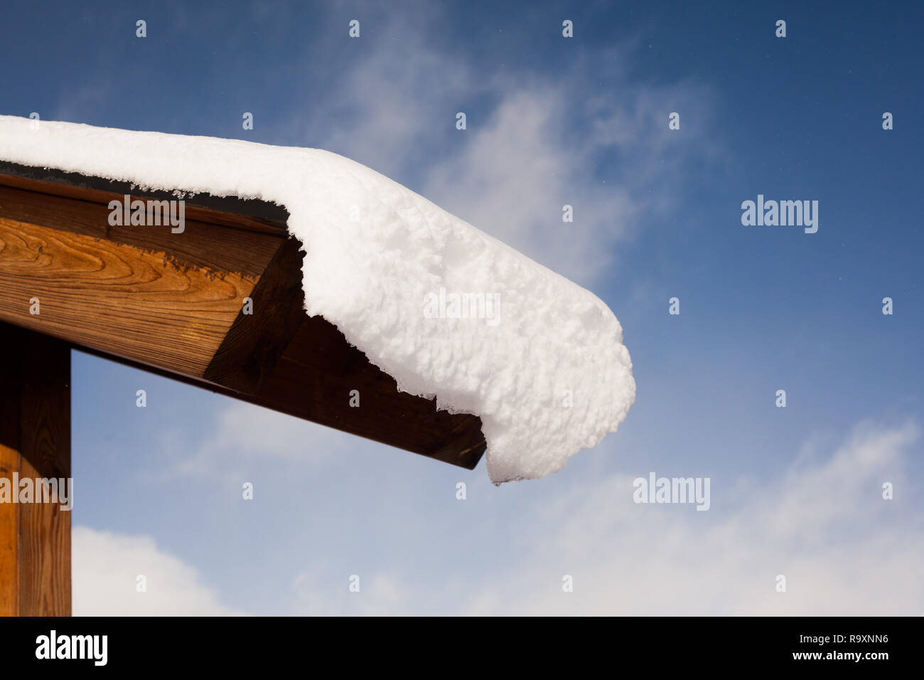 La neve del rotolamento fuori di legno del tetto ski chalet in Francia il pomeriggio soleggiato. Foto Stock