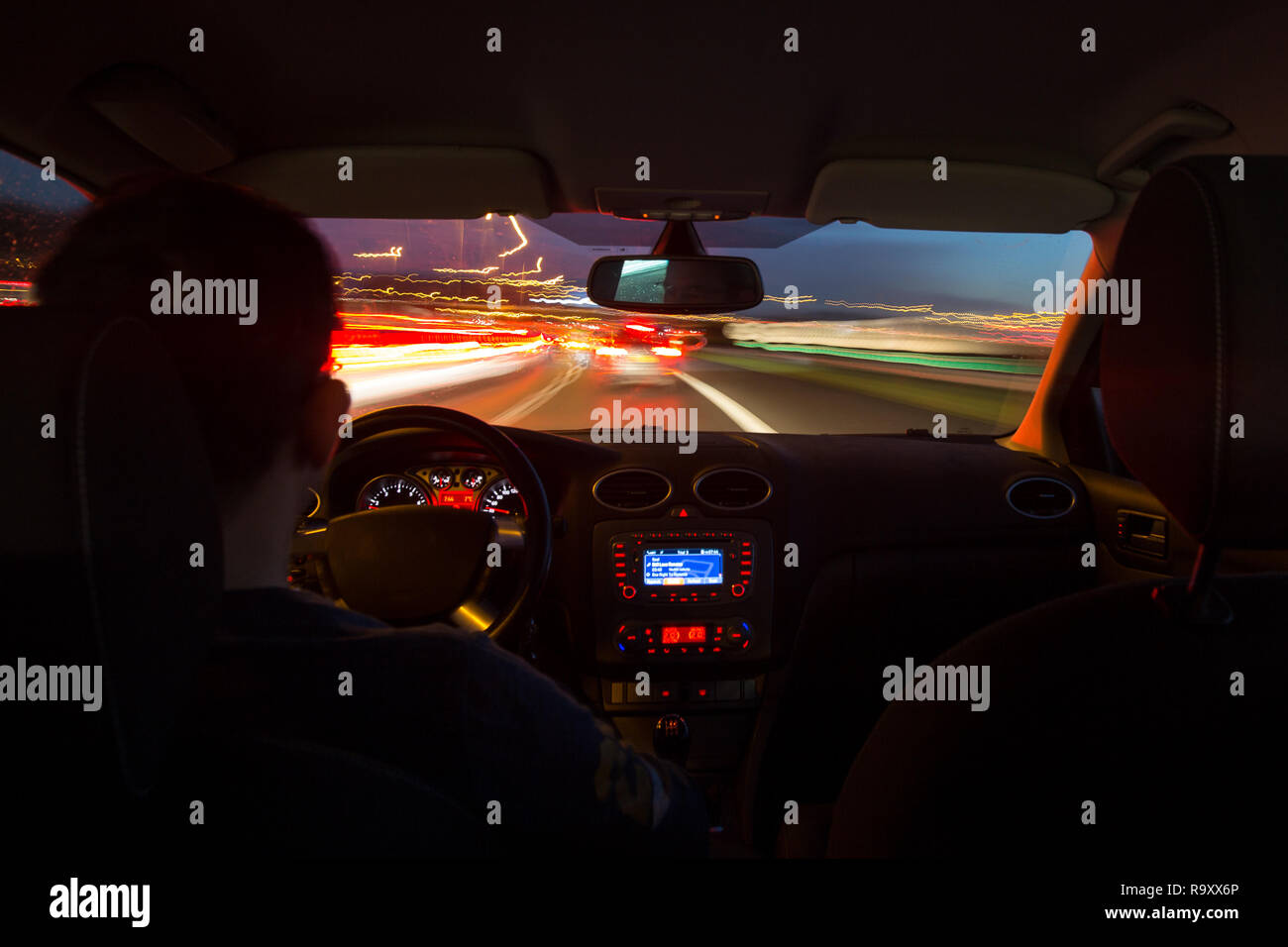 Strada di notte vista dall'interno di una vettura con le luci di strada e il movimento sfocati velocizzando le vetture in corrispondenza di una autostrada durante le ore di punta. Foto Stock