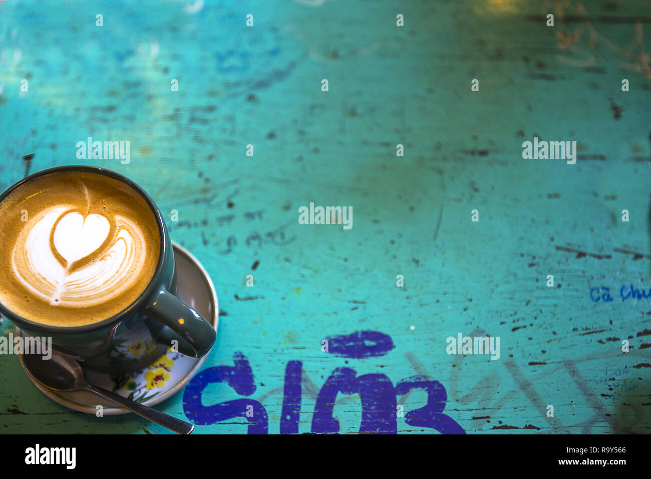 Una piccola tazza e piattino di cappuccino caffè su una tabella turquose. Foto Stock