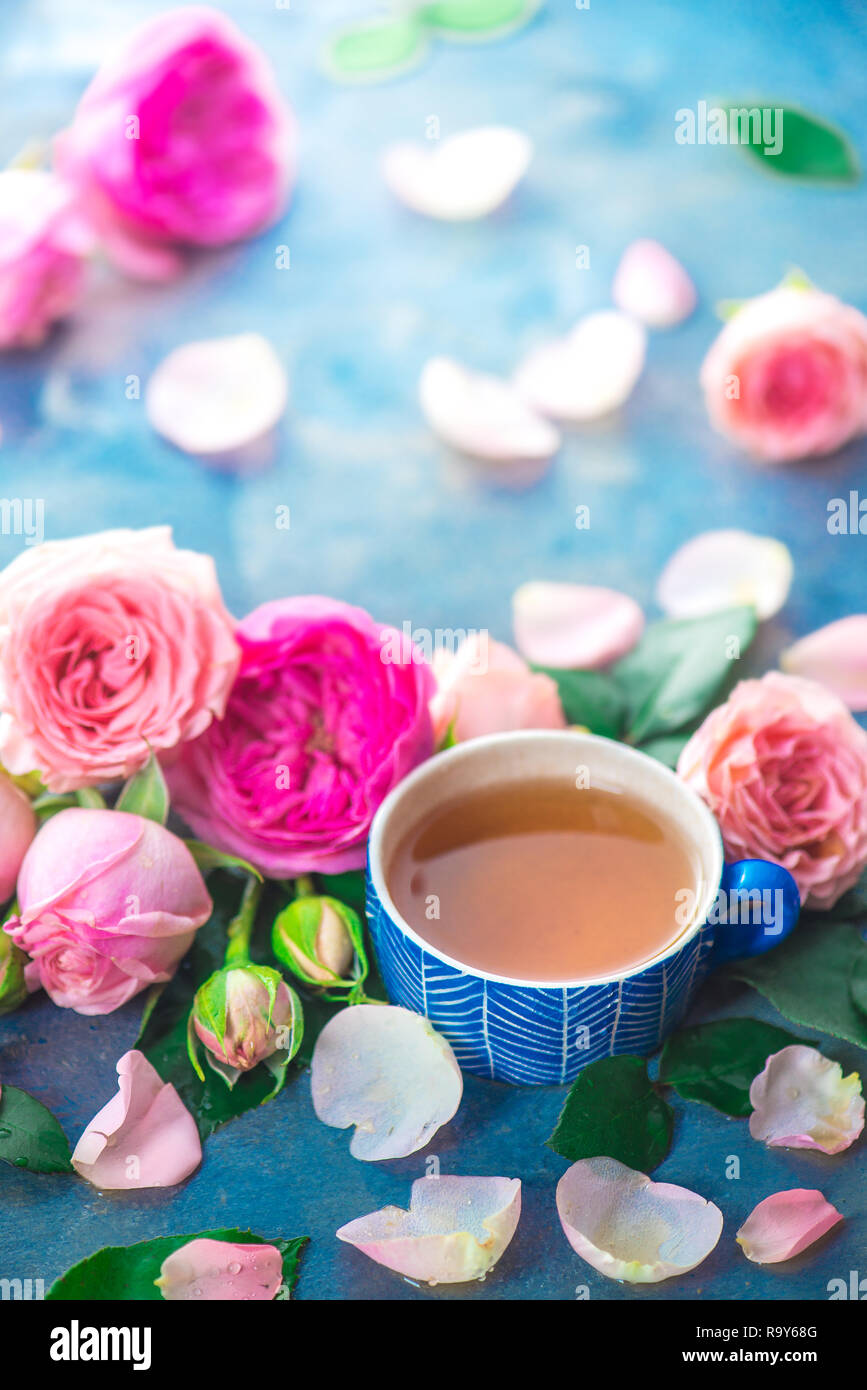 Rosa tea in ceramica tazze di tè e petali di fiori su fondo bagnato sfondo luminoso con copia spazio. Drink stagionali fotografia Foto Stock