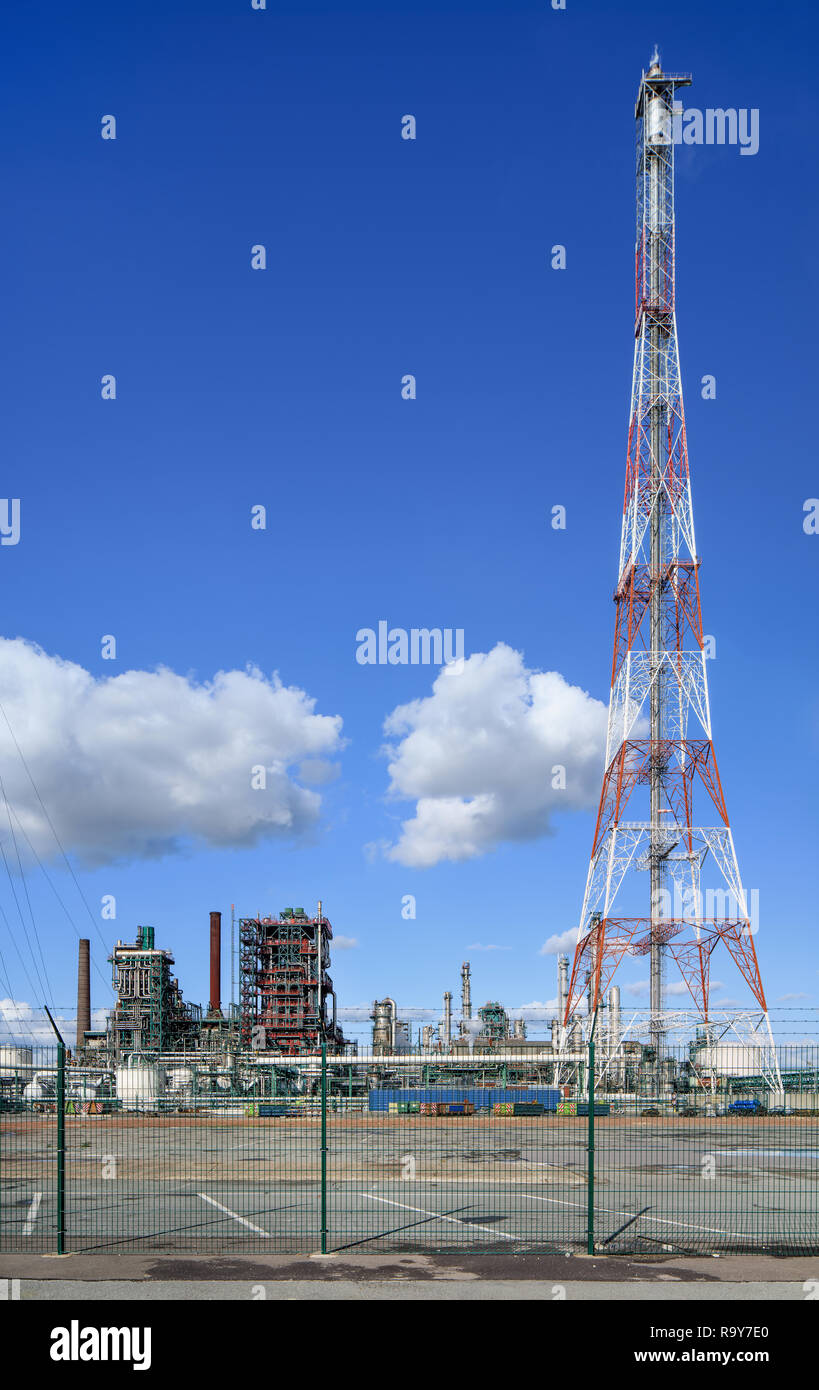 Il bianco e il rosso flare montante con una raffineria di petrolio sullo sfondo contro un cielo blu con nuvole drammatico, porto di Anversa, Belgio Foto Stock