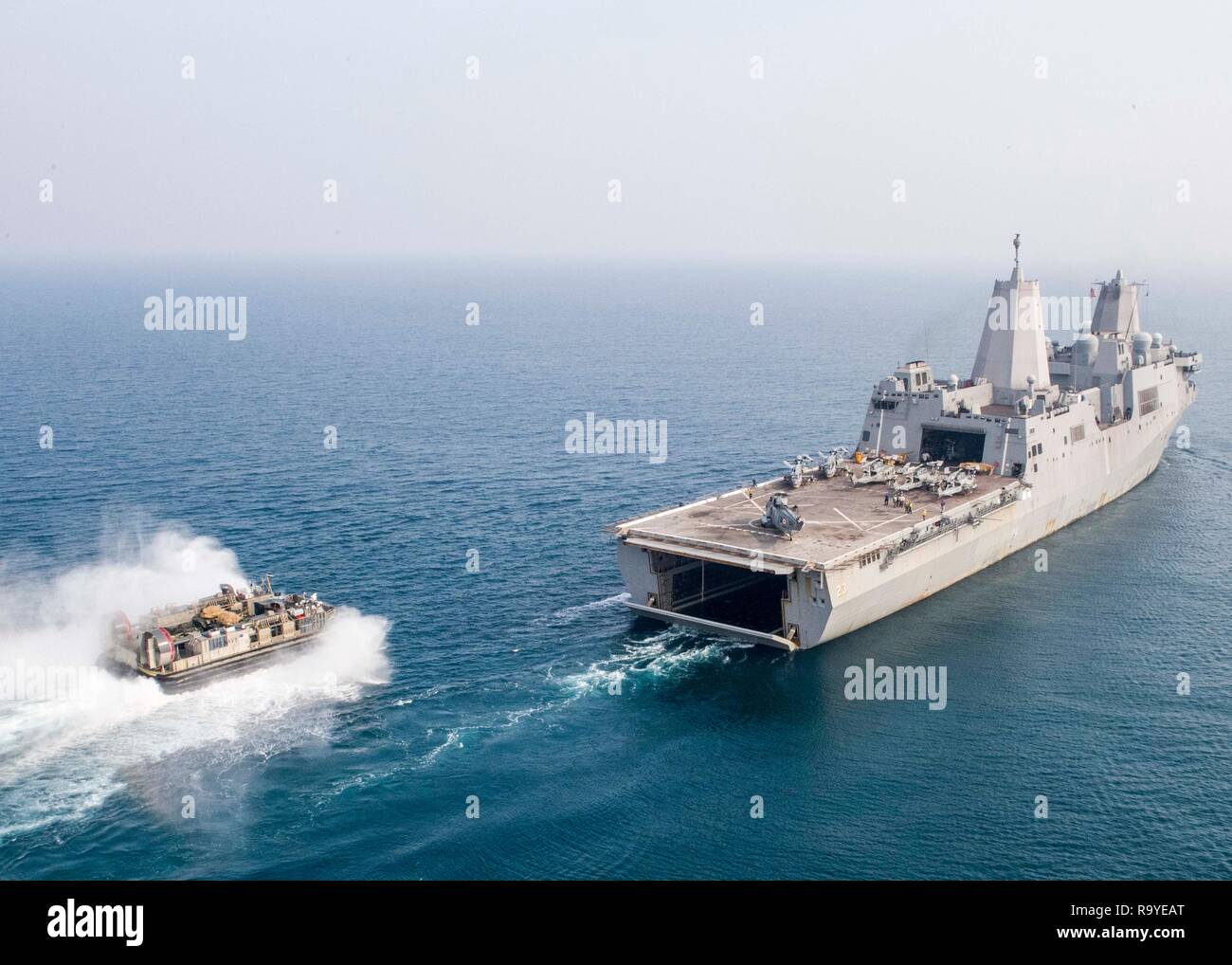 Un U.S. Navy landing craft, aria velocità cuscino dietro gli Stati Uniti La Marina di San Antonio-classe di trasporto anfibio dock nave USS Anchorage durante gli esercizi di cooperazione con la Marina indiana cacciatorpediniere INS Rajput 26 dicembre 2018 nell'Oceano Indiano. Foto Stock