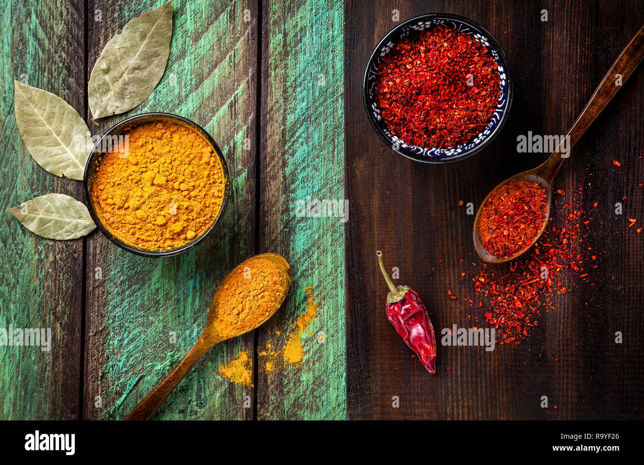 Peperoncino, la paprica, la curcuma e le foglie di alloro in legno verde e sfondo marrone Foto Stock