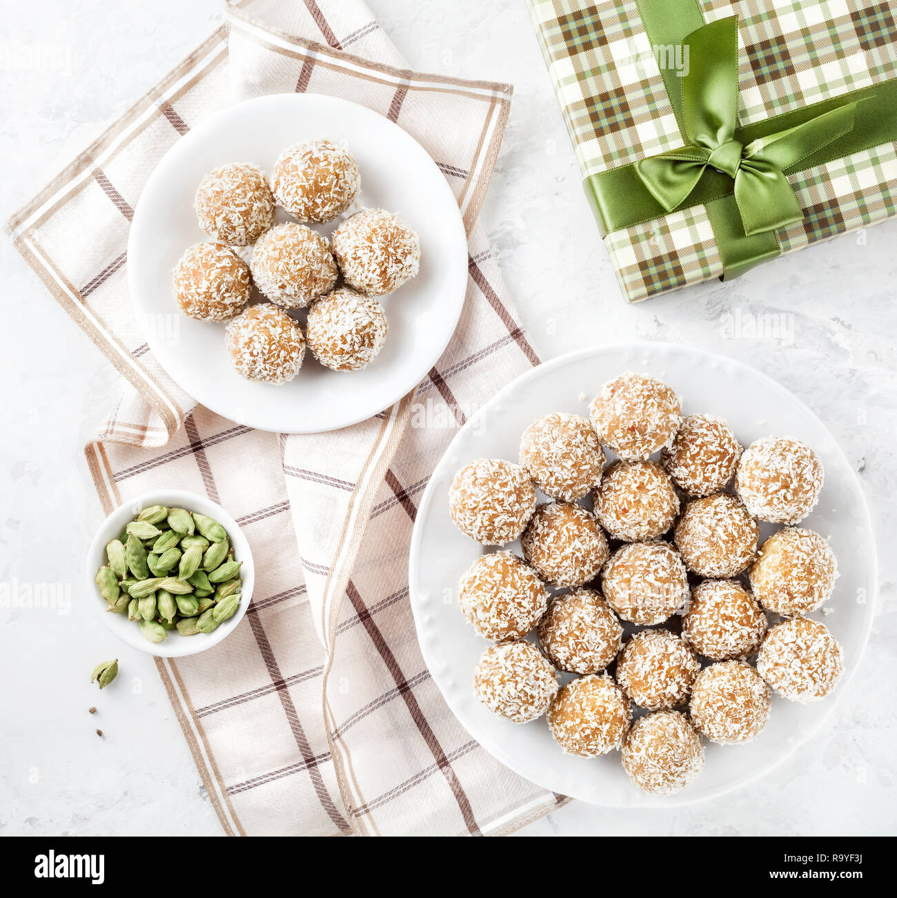 La farina di ceci indiano Ladoo con dadi e cardamomo verde nei pressi di green box regalo su sfondo bianco Foto Stock