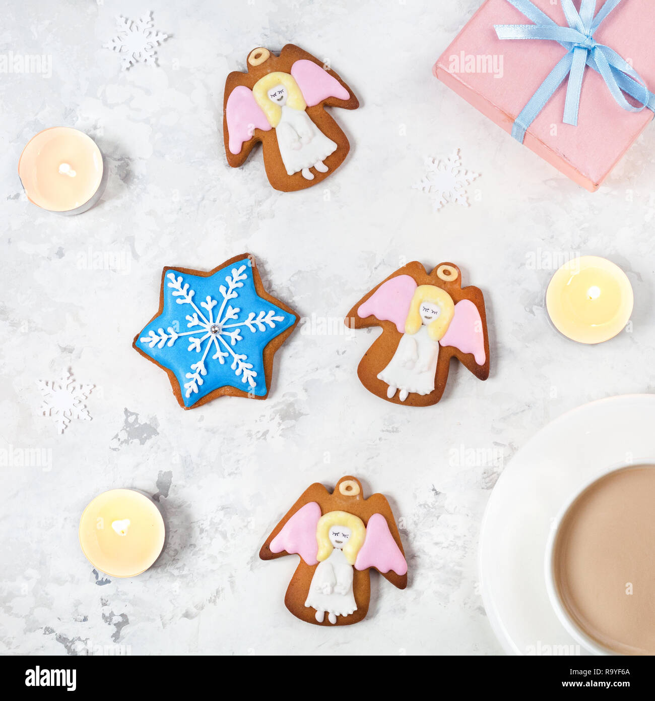 Angeli i cookie, confezione regalo e una tazza di caffè nei pressi di candele su sfondo bianco Foto Stock