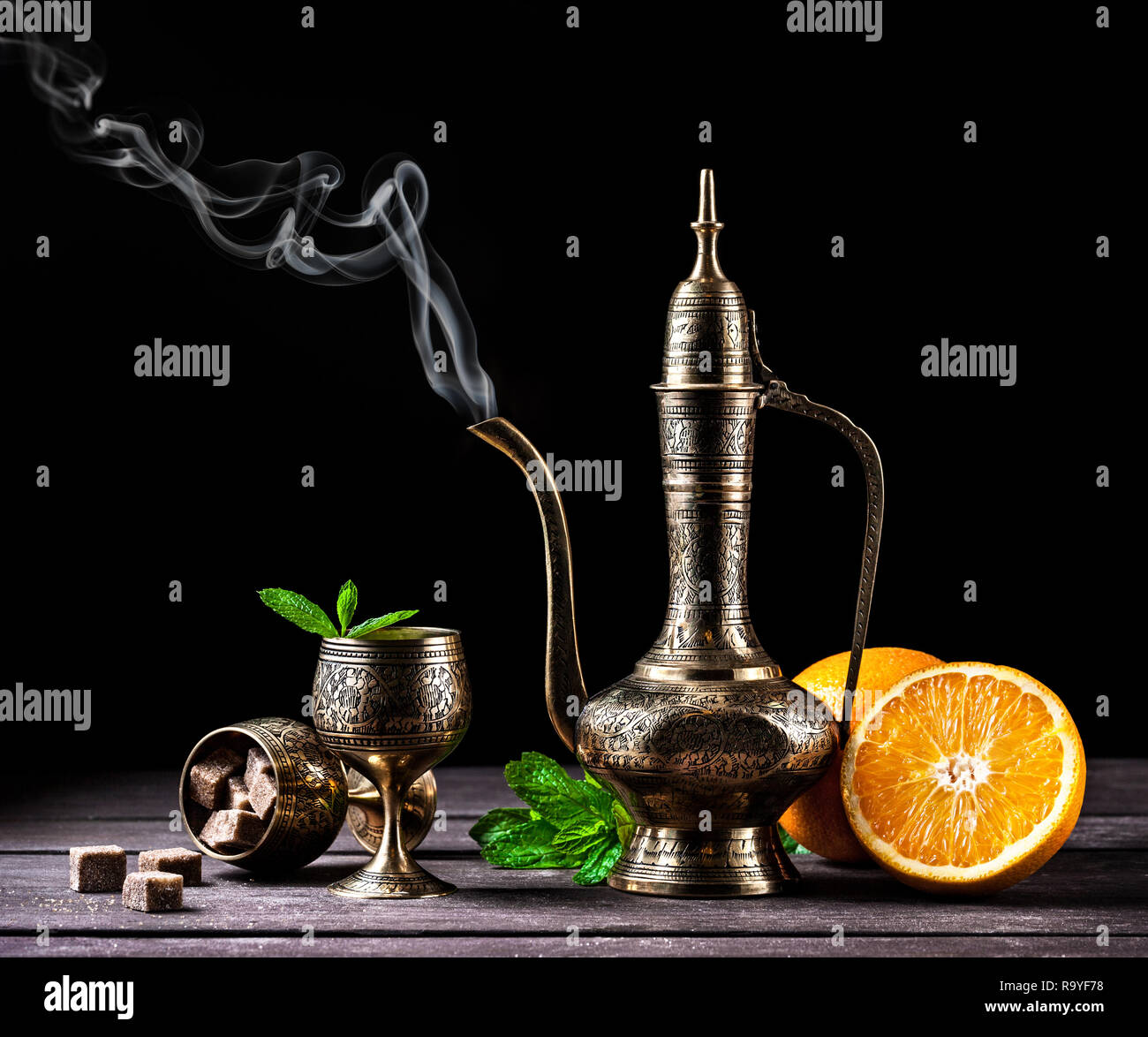 Tè marocchino alla menta e arance in oriental cooper pot e tazze sul rustico sfondo di legno Foto Stock