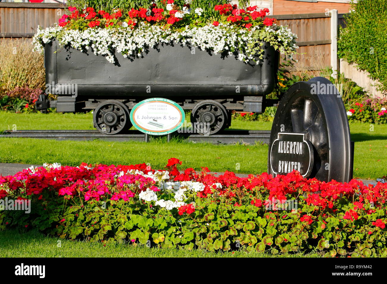 Un caldo benvenuto che accoglie i visitatori e i residenti per le miniere di carbone della Comunità Allerton Bywater, come un carrello di carbone & Treno ruote sono coperte di piante Foto Stock