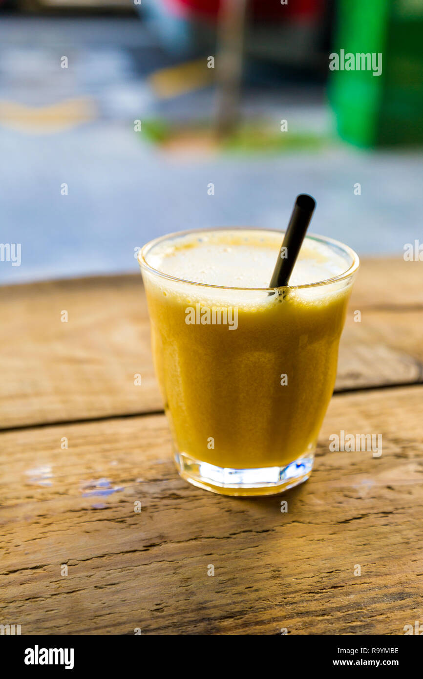 Bicchiere di succo d'arancia fresco con una paglia su una tavola di legno in un cafe (Valencia, Spagna) Foto Stock