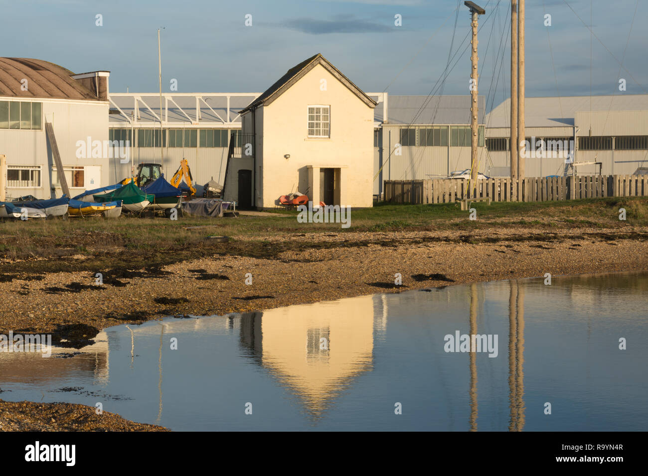 Staniforth Cottage, un edificio classificato Grade II su Calshot spit riflessa nel Solent. Era un edificio di guardia costiera, convertiti in uso militare. Foto Stock