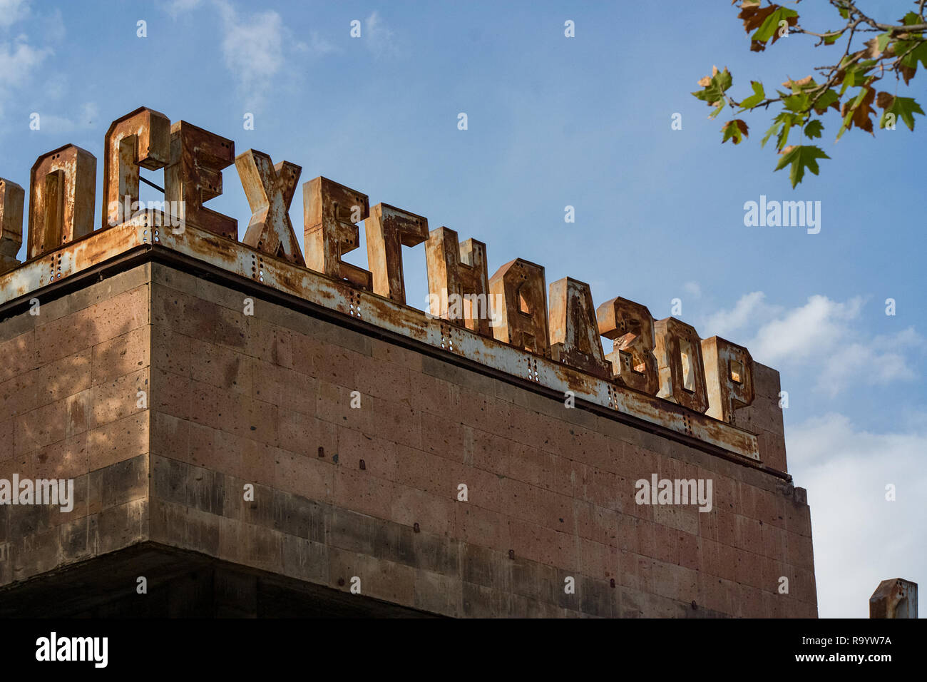 Un Soviet vecchio 3D Cartello in metallo sulla parte superiore di un cartello stradale edificio in Armenia. Foto Stock