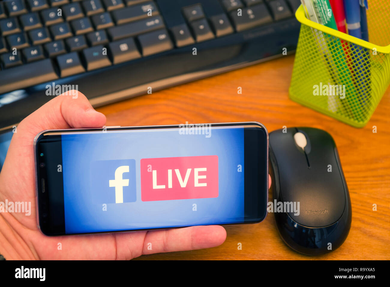 PIATRA NEAMT, Romania - 30 luglio 2018: mano trattiene un Samsung S8+ con Facebook Live logo sullo schermo, Ufficio dello sfondo. Foto Stock