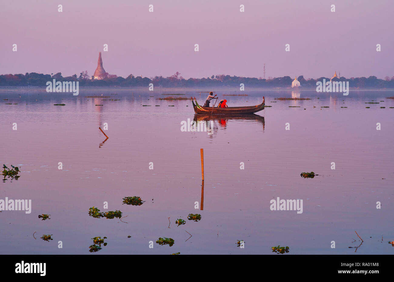 La superficie trasparente del lago Taungthaman con riflessi Cielo di tramonto, floating canoe e banca verde di Amarapura sullo sfondo, Mandalay Myanmar. Foto Stock