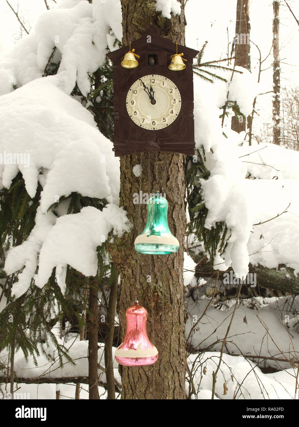 Orologio decorato con giocattoli di Natale in inverno bosco su un abete coperto di neve. L'orologio a cinque minuti a dodici. Foto Stock