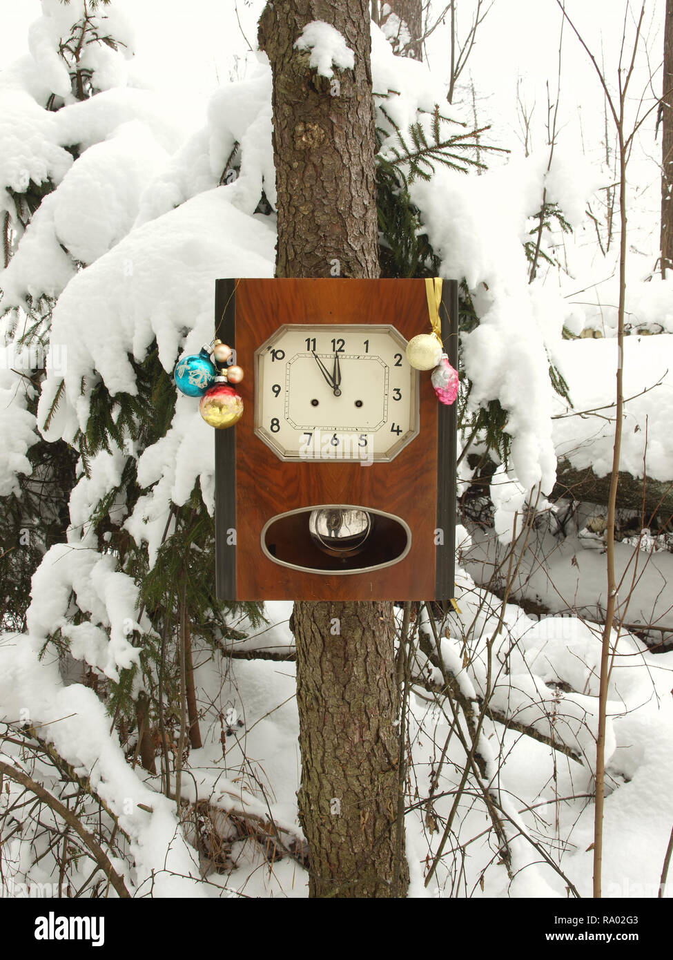 Orologio decorato con giocattoli di Natale in inverno bosco su un abete coperto di neve. L'orologio a cinque minuti a dodici. Foto Stock