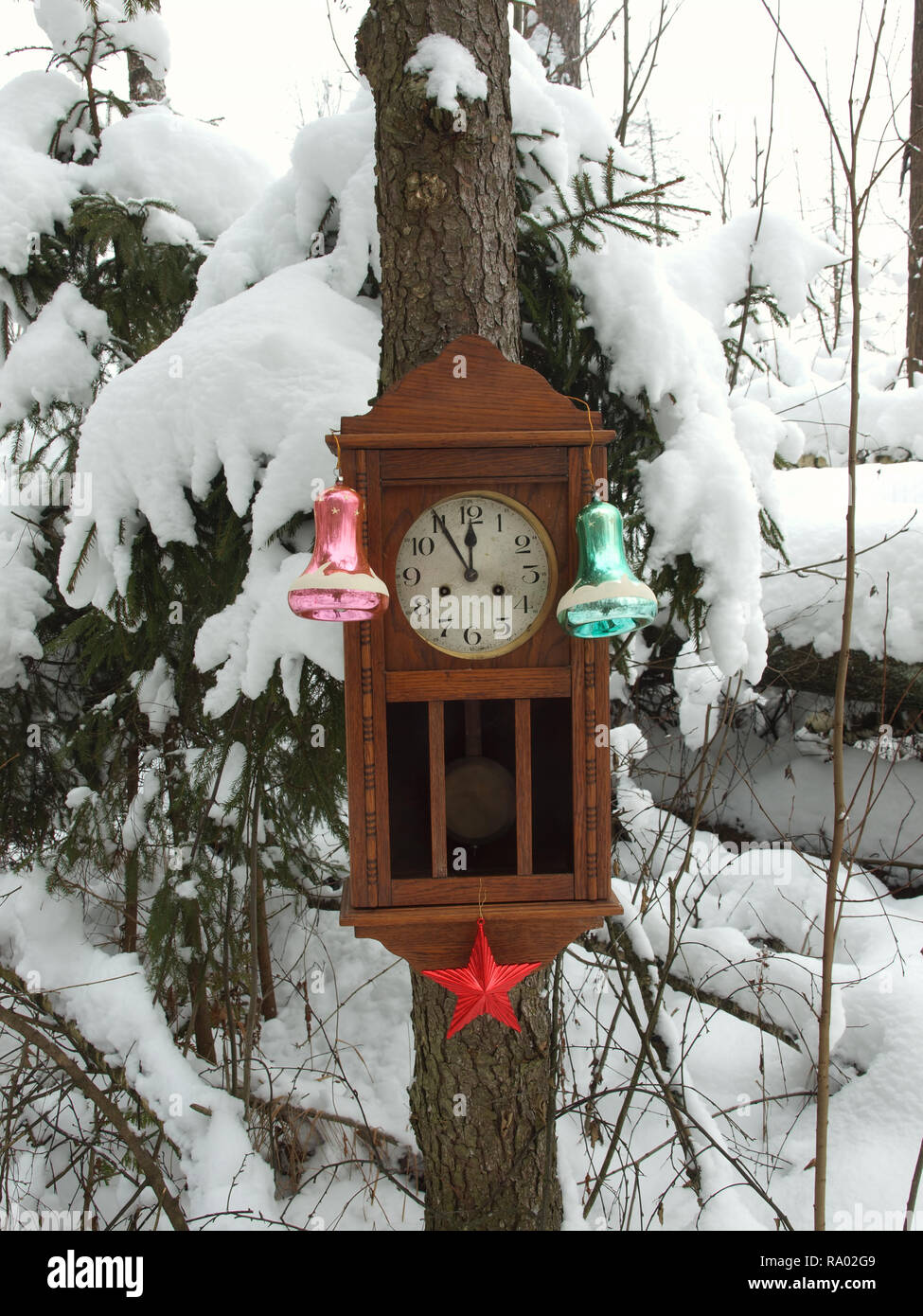 Orologio decorato con giocattoli di Natale in inverno bosco su un abete coperto di neve. L'orologio a cinque minuti a dodici. Foto Stock
