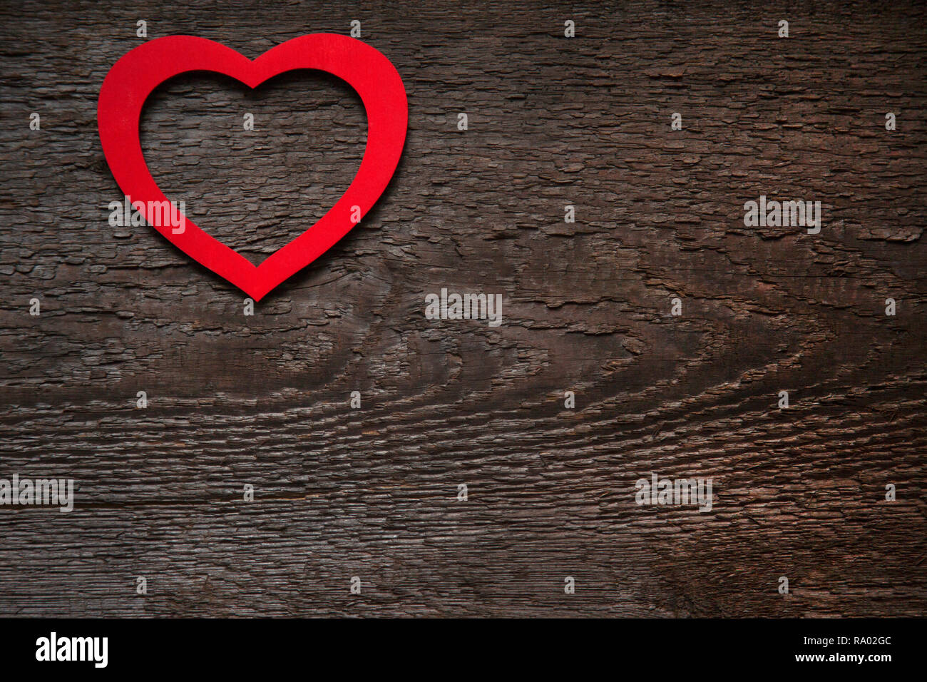 Il cuore rosso è situato su un vecchio legno marrone scheda secco. Il giorno di San Valentino card Foto Stock