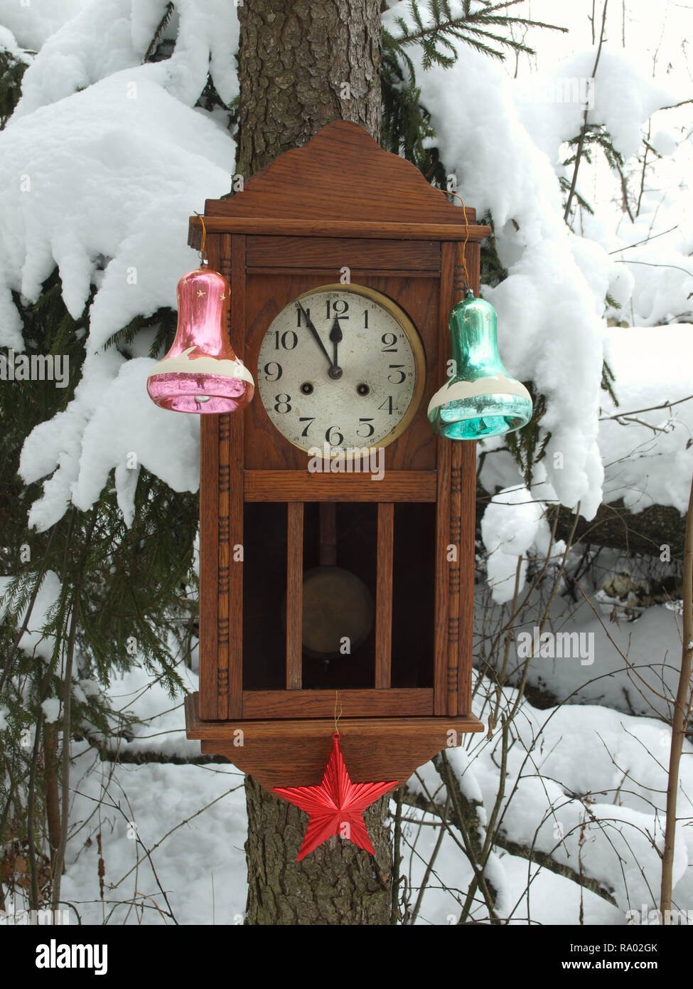 Orologio decorato con giocattoli di Natale in inverno bosco su un abete coperto di neve. L'orologio a cinque minuti a dodici. Foto Stock