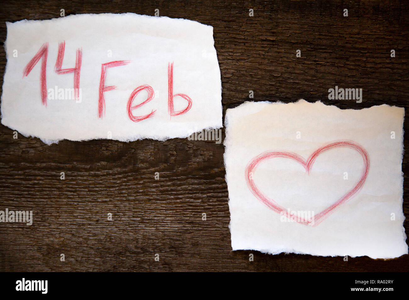 Febbraio 14 è scritta in rosso matita su un pezzo di carta, il cuore è disegnata a matita rossa su un pezzo di carta, tutto ciò che si trova sul vecchio pannello di legno Foto Stock