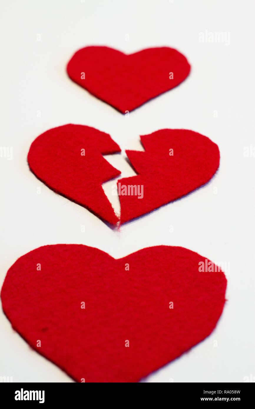 La rottura di un feltro rosso cuore tra due interi cuori. Heartbreak e l'amore. Foto Stock