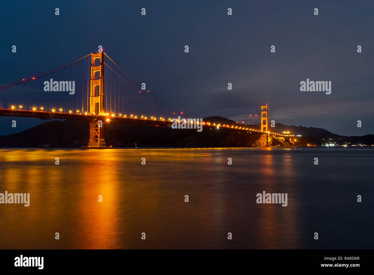 Vista notturna del Ponte Golden Gate riflessa nell'acqua sfocata la superficie della baia di San Francisco, California Foto Stock