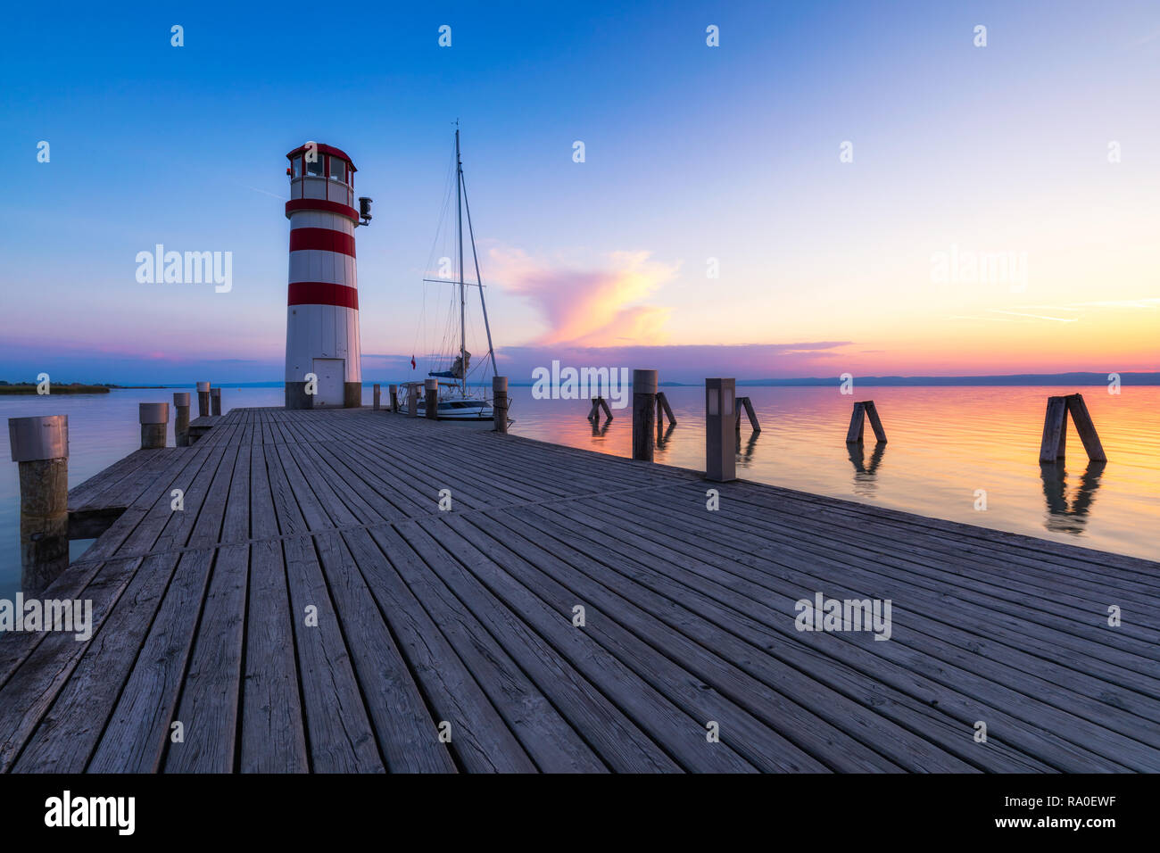 Faro di lago di Neusiedl, Podersdorf am See, Burgenland, Austria. Faro al tramonto in Austria. Il molo di legno con il faro in Podersdorf sul lak Foto Stock
