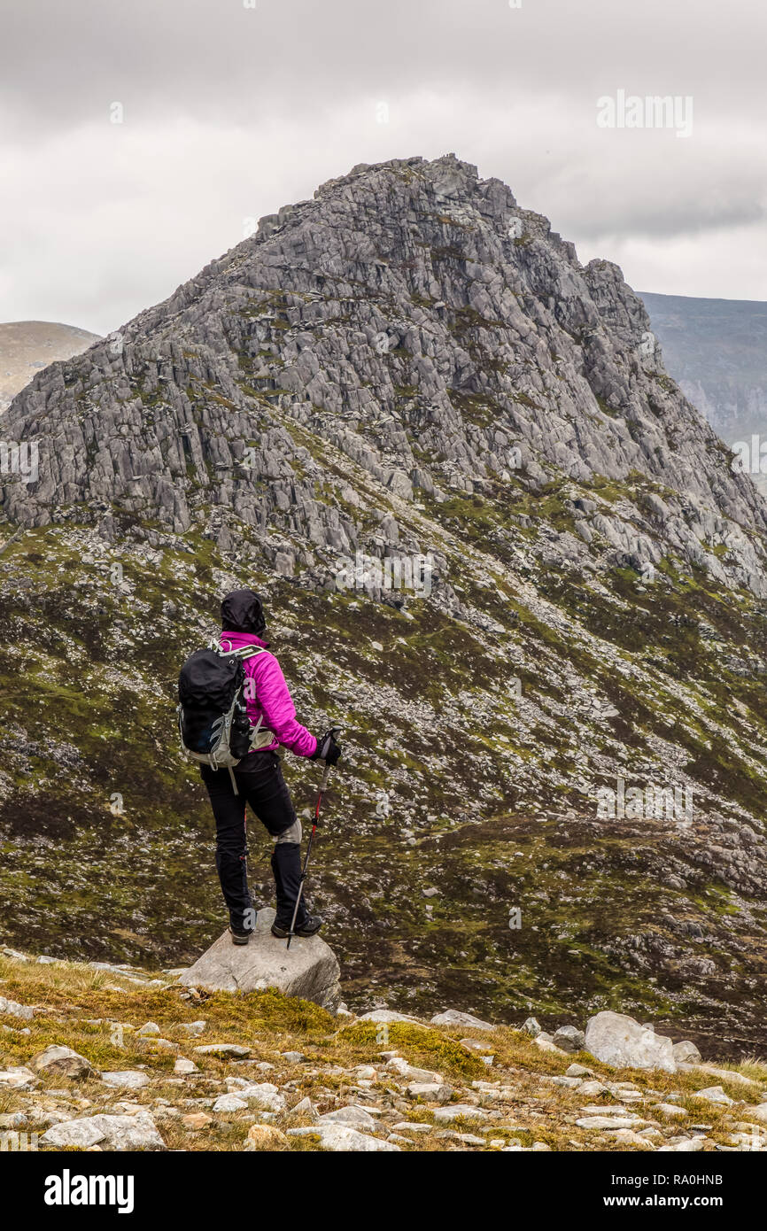 Femmina Lone walker guardando verso Tryfan dalla parte inferiore pendici meridionali di Glyder Fach nel Parco Nazionale di Snowdonia nel Galles del Nord. Foto Stock