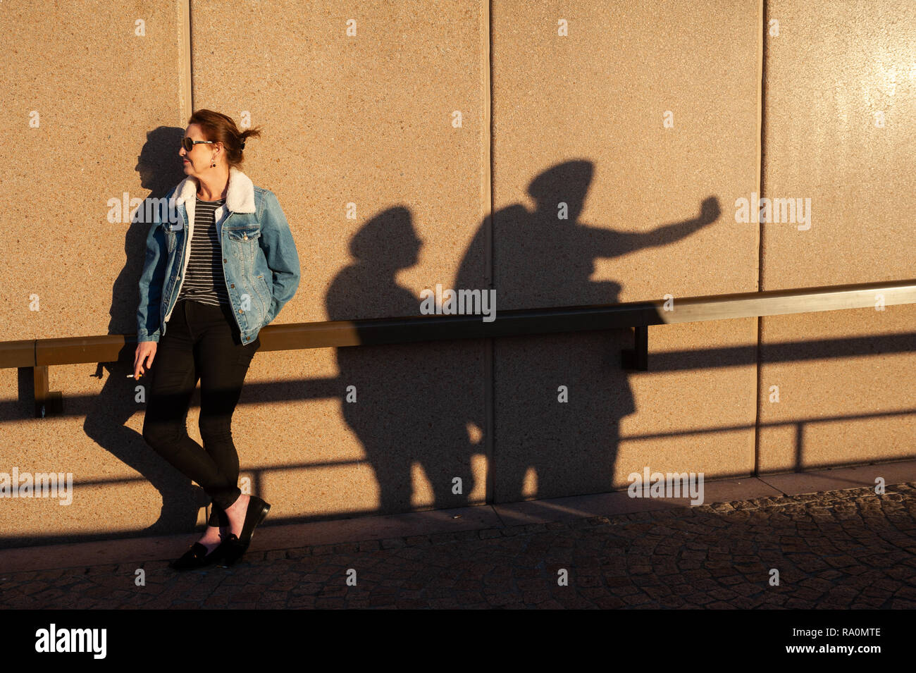 16.09.2018, Sydney, Nuovo Galles del Sud, Australien - Eine Frau geniesst die Abendsonne waehrend sie am Circular Quay eine Zigarette raucht und neben ihr Foto Stock