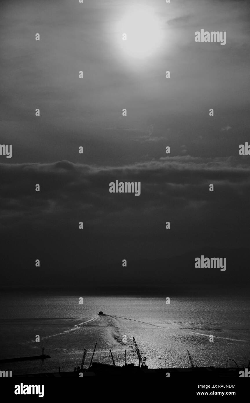 Ombre di sagome di barca nel mare Adriatico con trend con orizzonte di riferimento e la collina in background,in bianco e nero Foto Stock