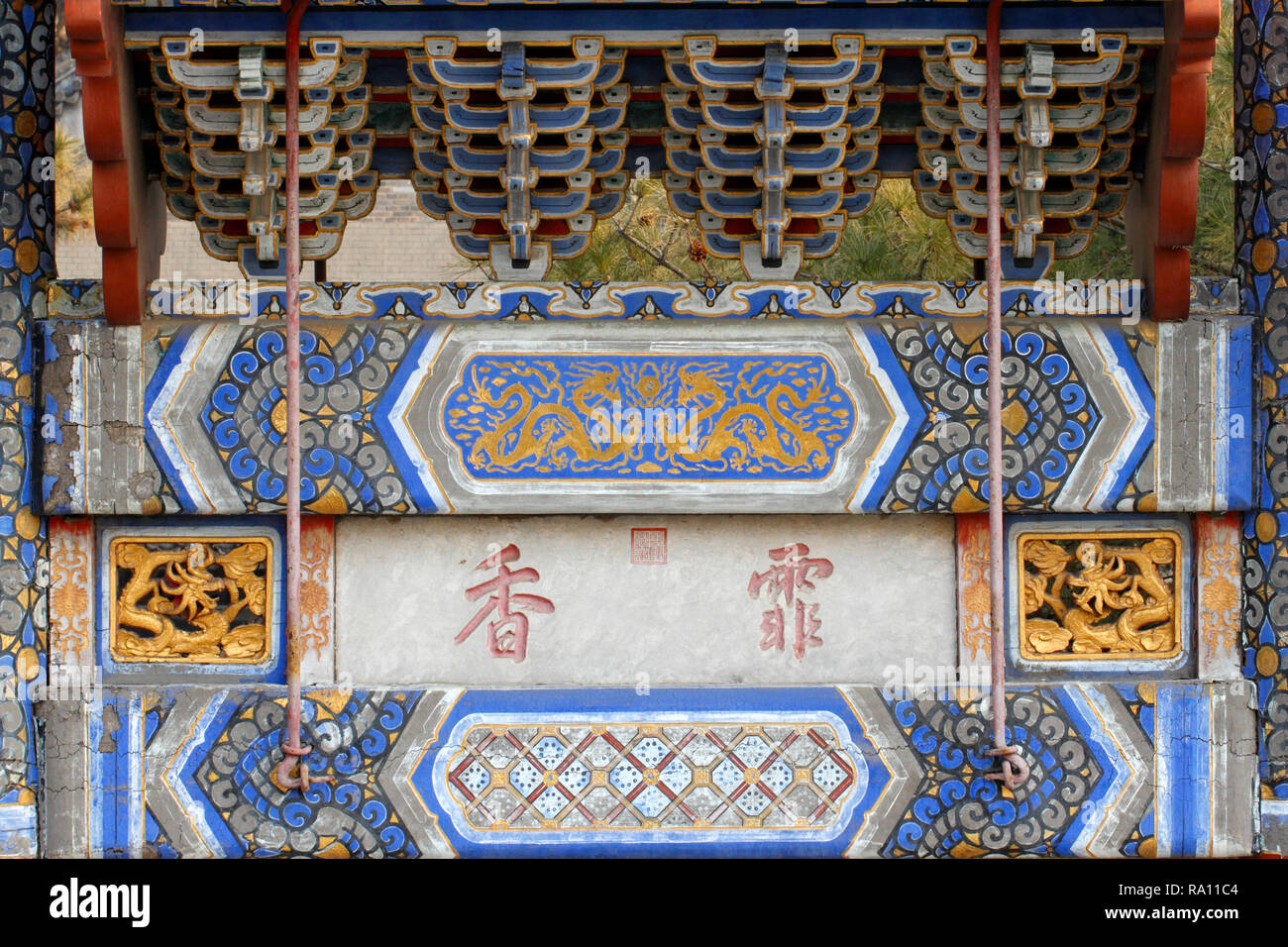 Oro rosso e blu dipinto sul fascio di antico edificio, include motivi del drago. Palazzo Estivo, Pechino, Repubblica Popolare Cinese. Foto Stock