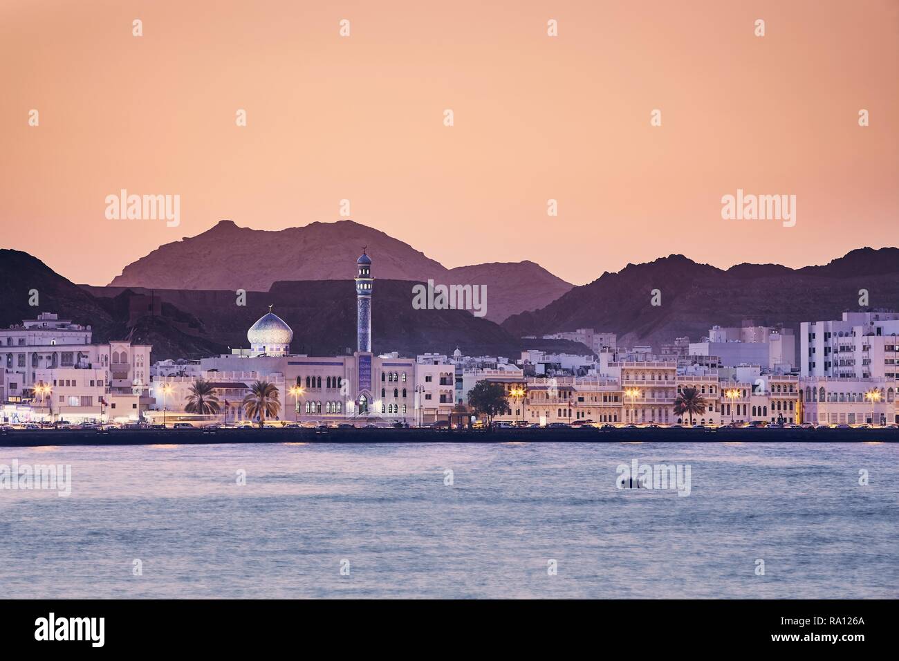 Paesaggio urbano in vista della città di Muscat al tramonto dorato. Il capitale di Oman. Foto Stock