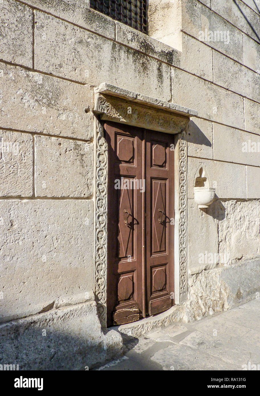 Una porta di legno con la pietra di surround e attraversa graffiato nel lavoro in pietra Foto Stock