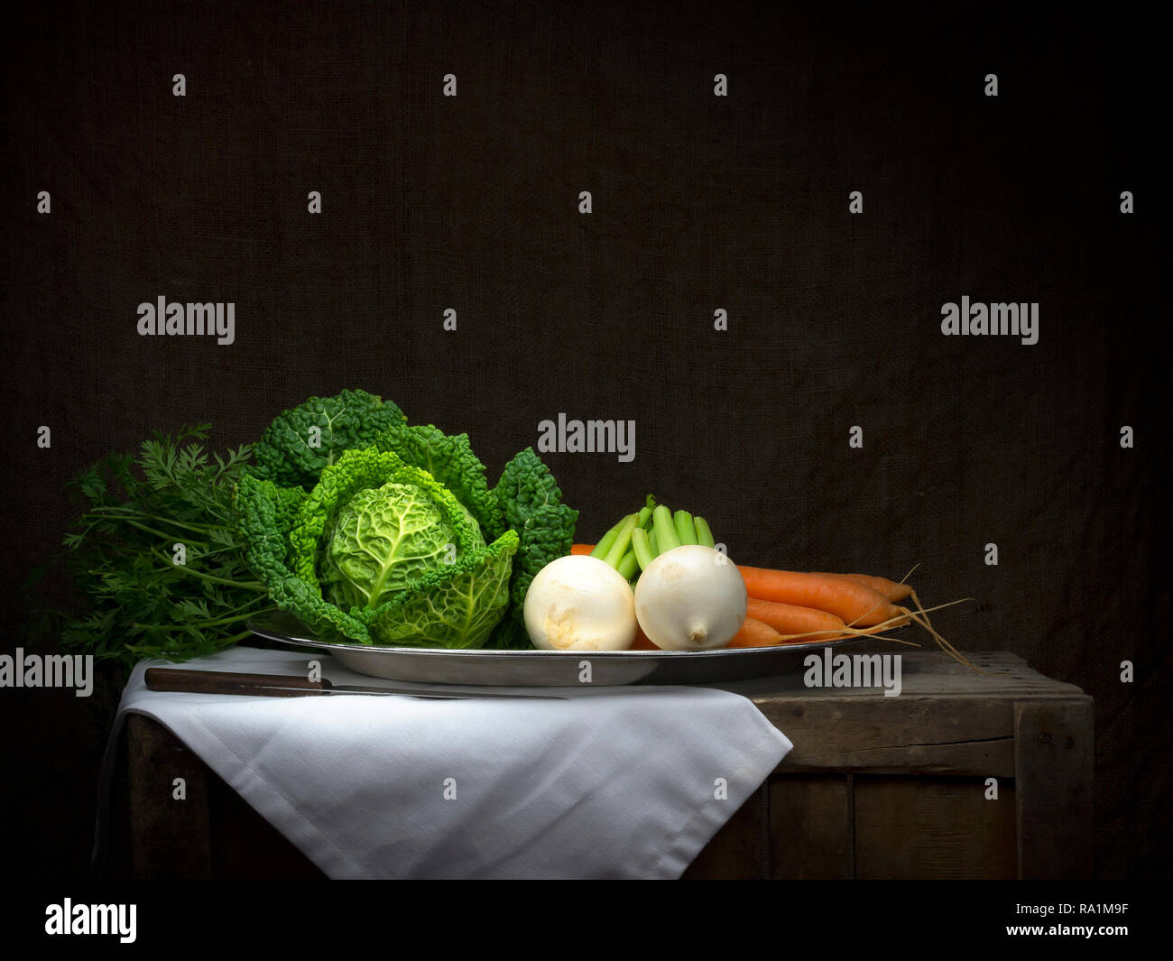 Ortaggio invernale platter, still life, chiaroscuro in stile barocco. La pittura di luce. Cavolo, carote, rape. Con il coltello da cucina. Foto Stock