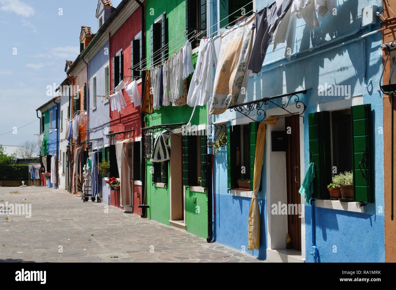 Case colorate in una zona residenziale di Burano nella laguna veneziana, Italia. Nota Il servizio lavanderia essiccazione su linee di abbigliamento esterno. Foto Stock