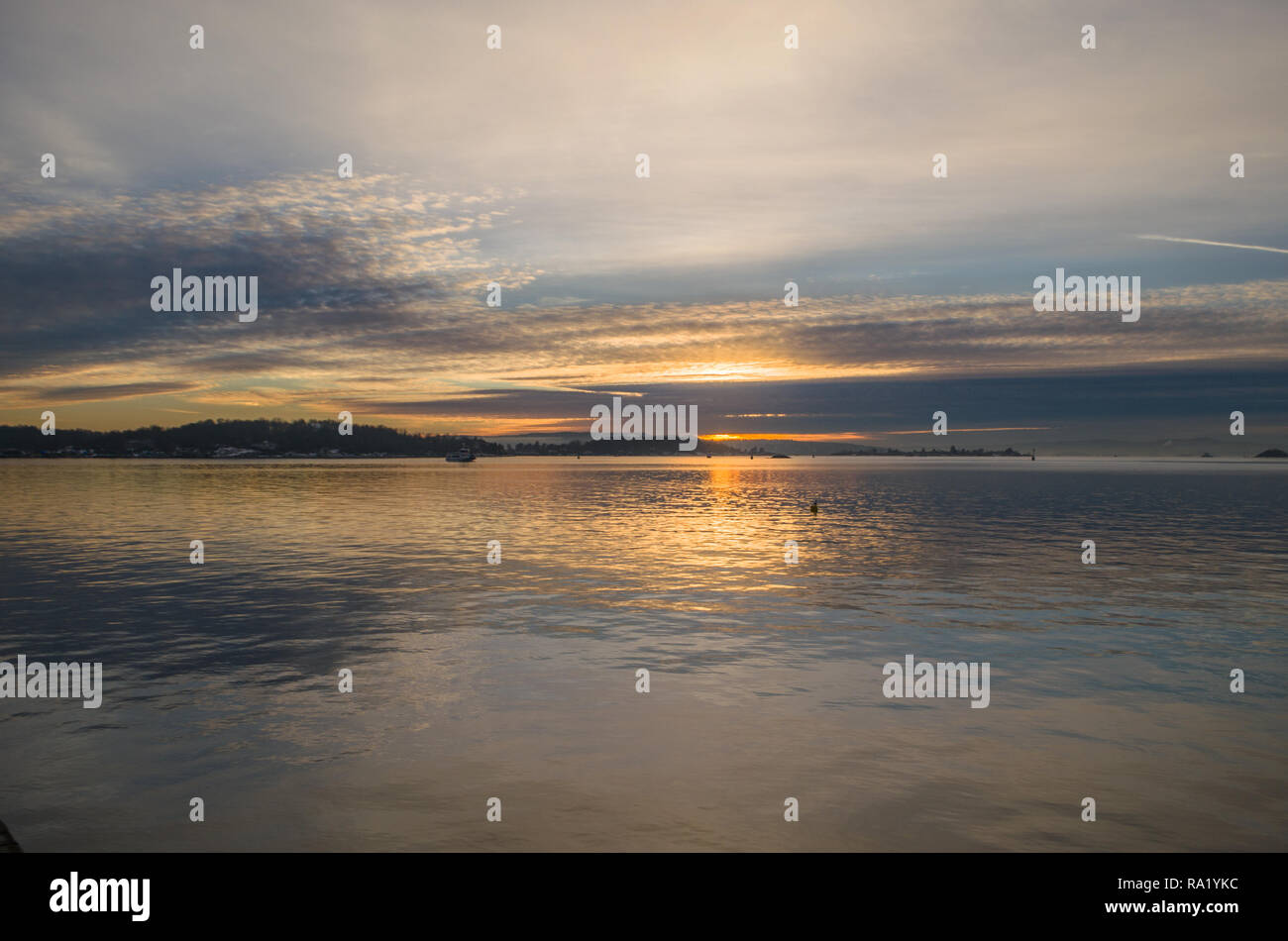 Tramonto dorato nella parte interna di Oslofjord nella calma giorno d'inverno. Foto Stock