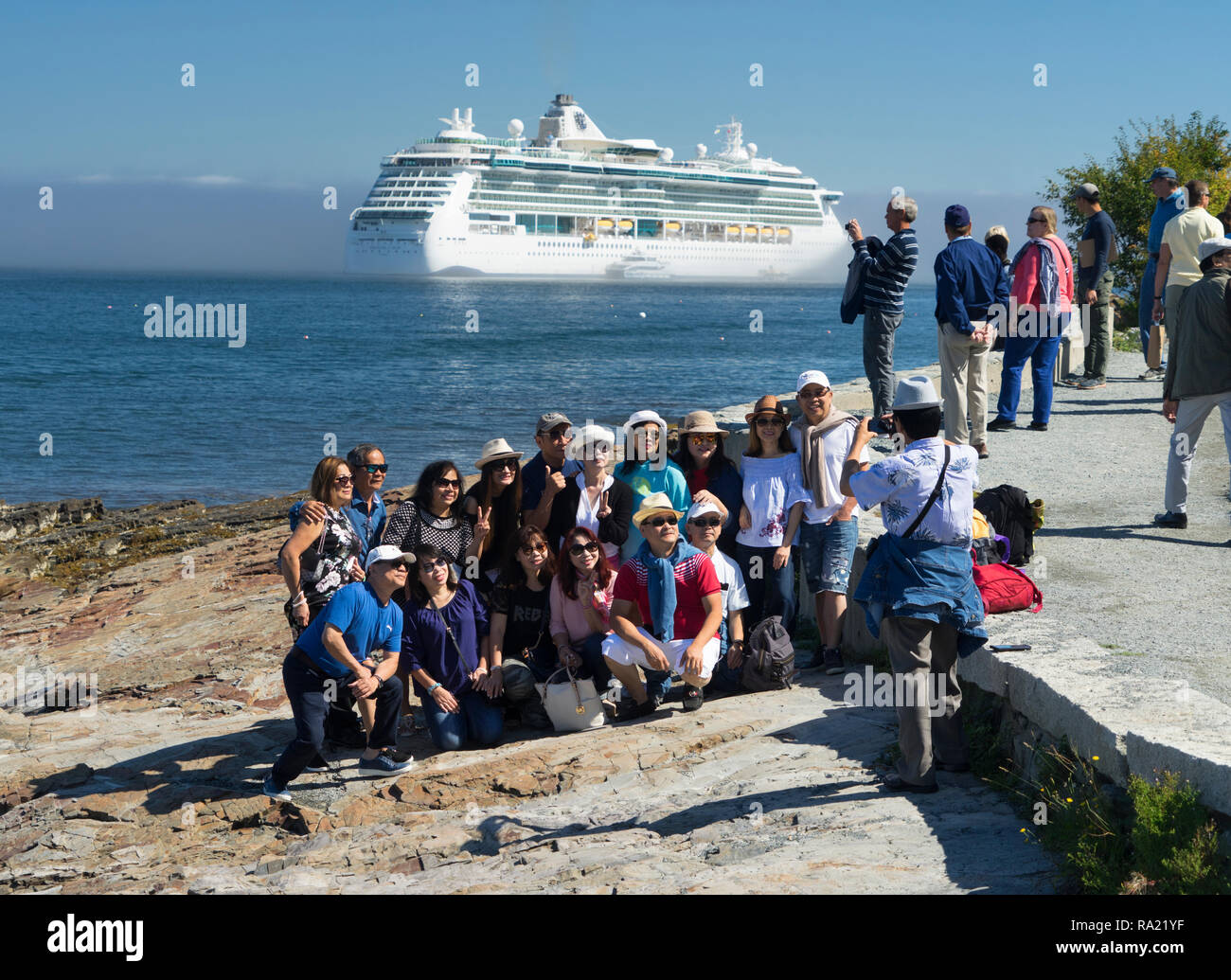 Turisti asiatici di prendere una foto di gruppo con una nave da crociera in background, Bar Harbor, Maine, Stati Uniti d'America. Foto Stock
