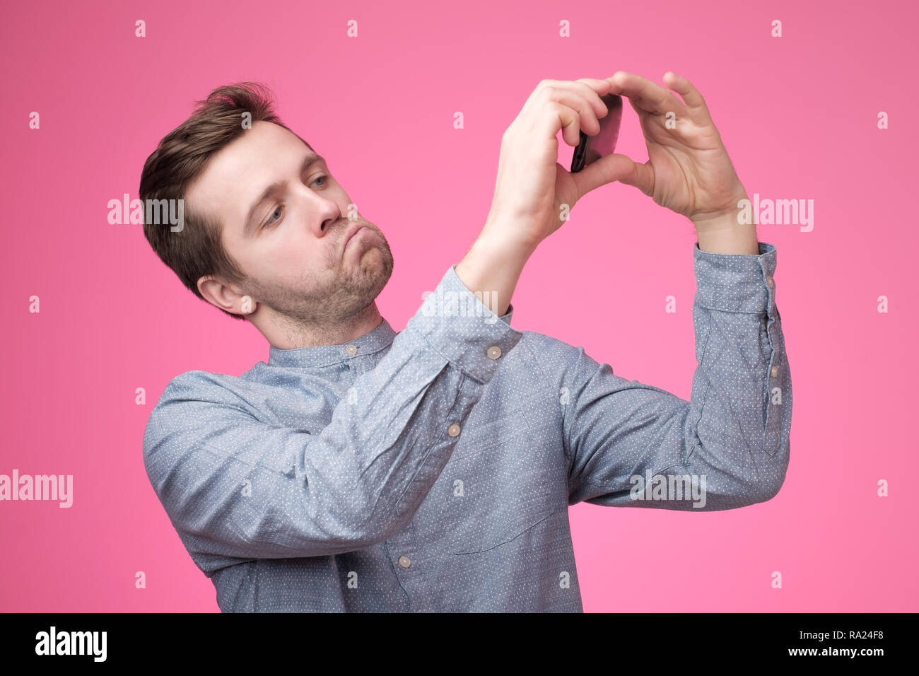 Ritratto di un allegro bel giovane uomo prendendo selfie sul suo telefono cellulare Foto Stock