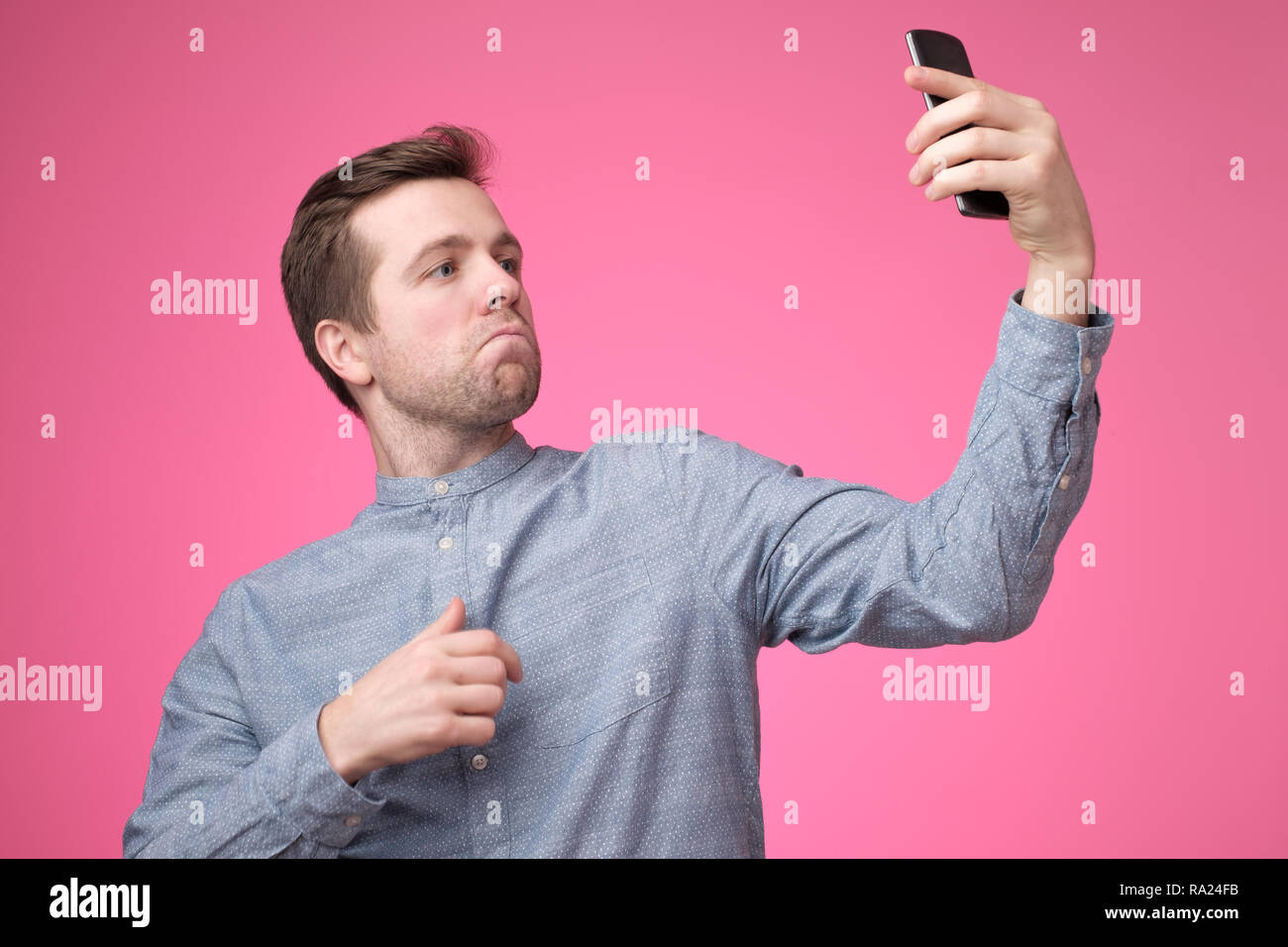 Ritratto di un allegro bel giovane uomo prendendo selfie sul suo telefono cellulare Foto Stock