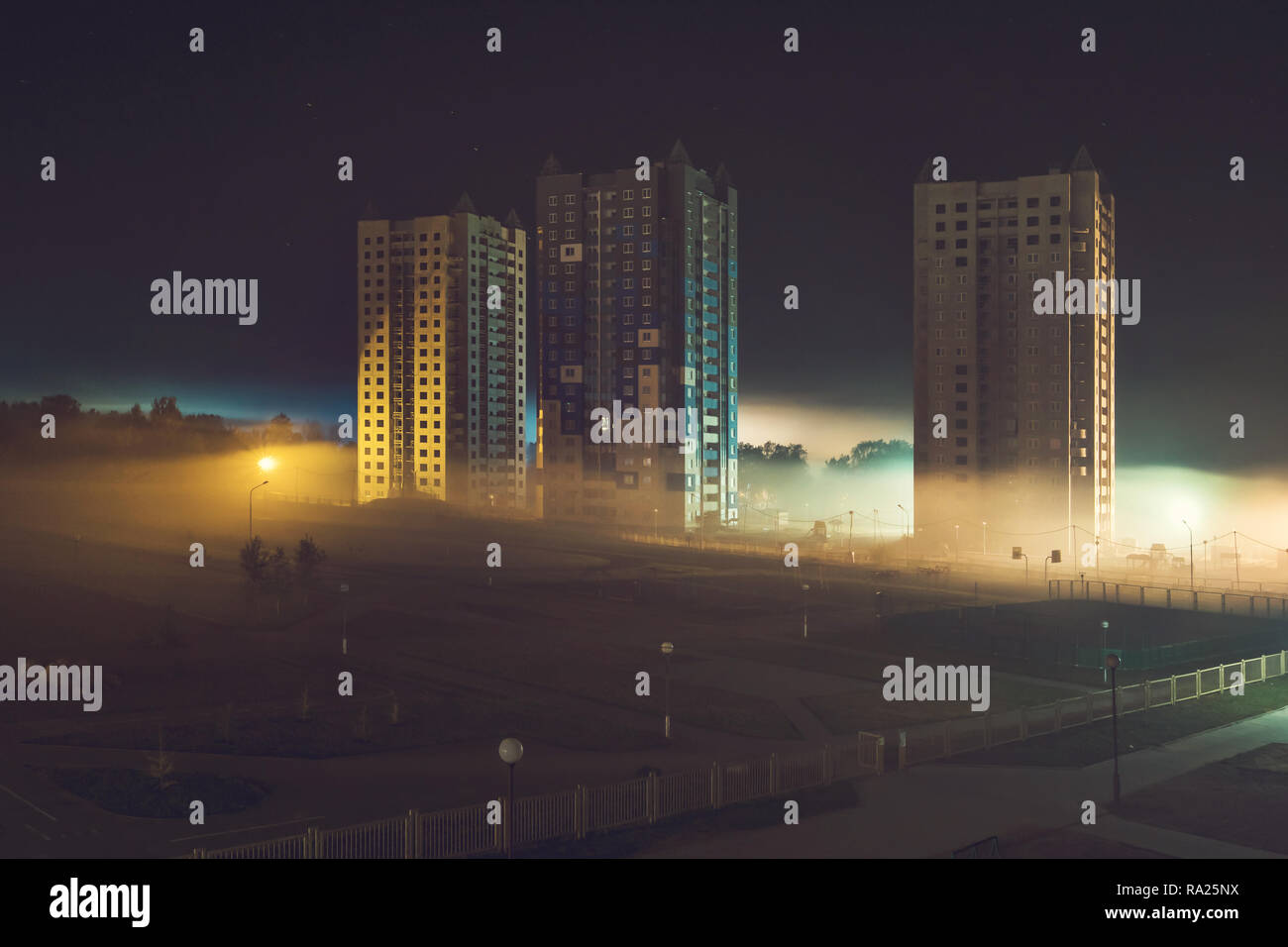 Panorama notturno della zona residenziale con edifici ad alta nella nebbia di mattina presto Foto Stock