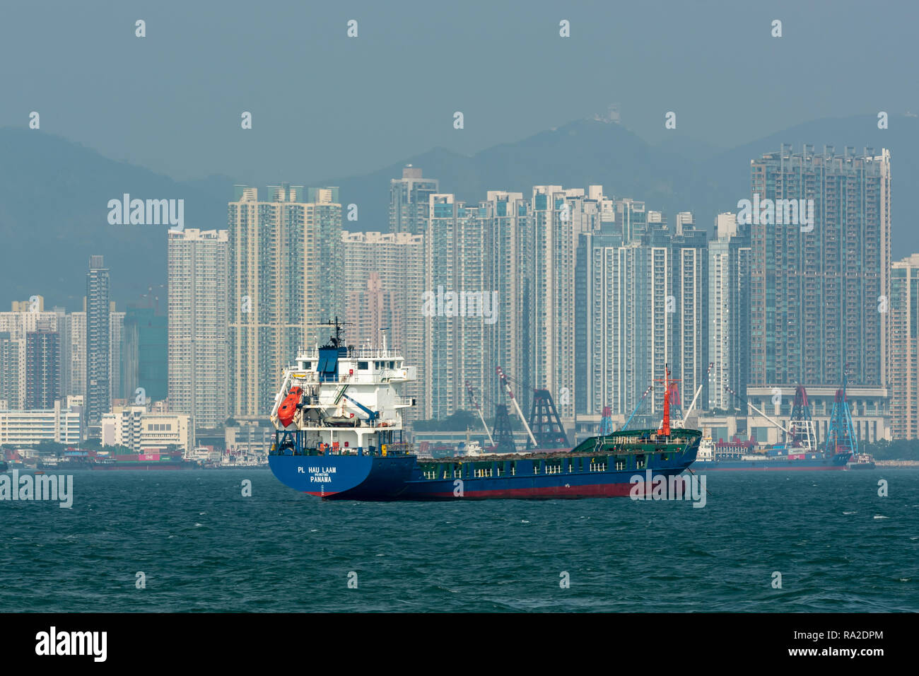 Il contrassegnato panamense nave da carico generale " PL Hau Kit LAAM' ormeggiato a Tai Kok Tsui in Hong Kong con imponenti blocchi di appartamenti sfrangiare il porto. Foto Stock