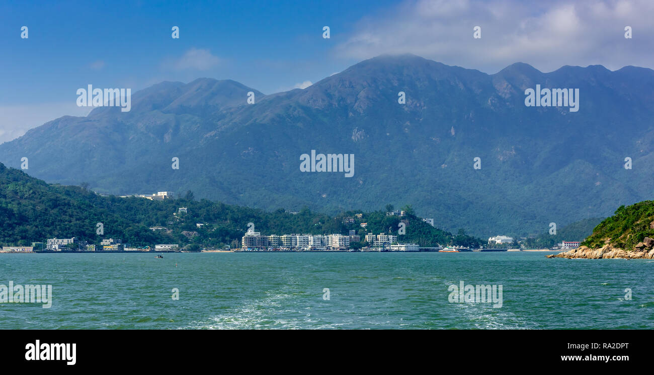 I picchi gemelli di Lantau Island, Tramonto e picchi di Lantau dominano i bassi appartamenti fodera riva del Silvermine Bay. Foto Stock