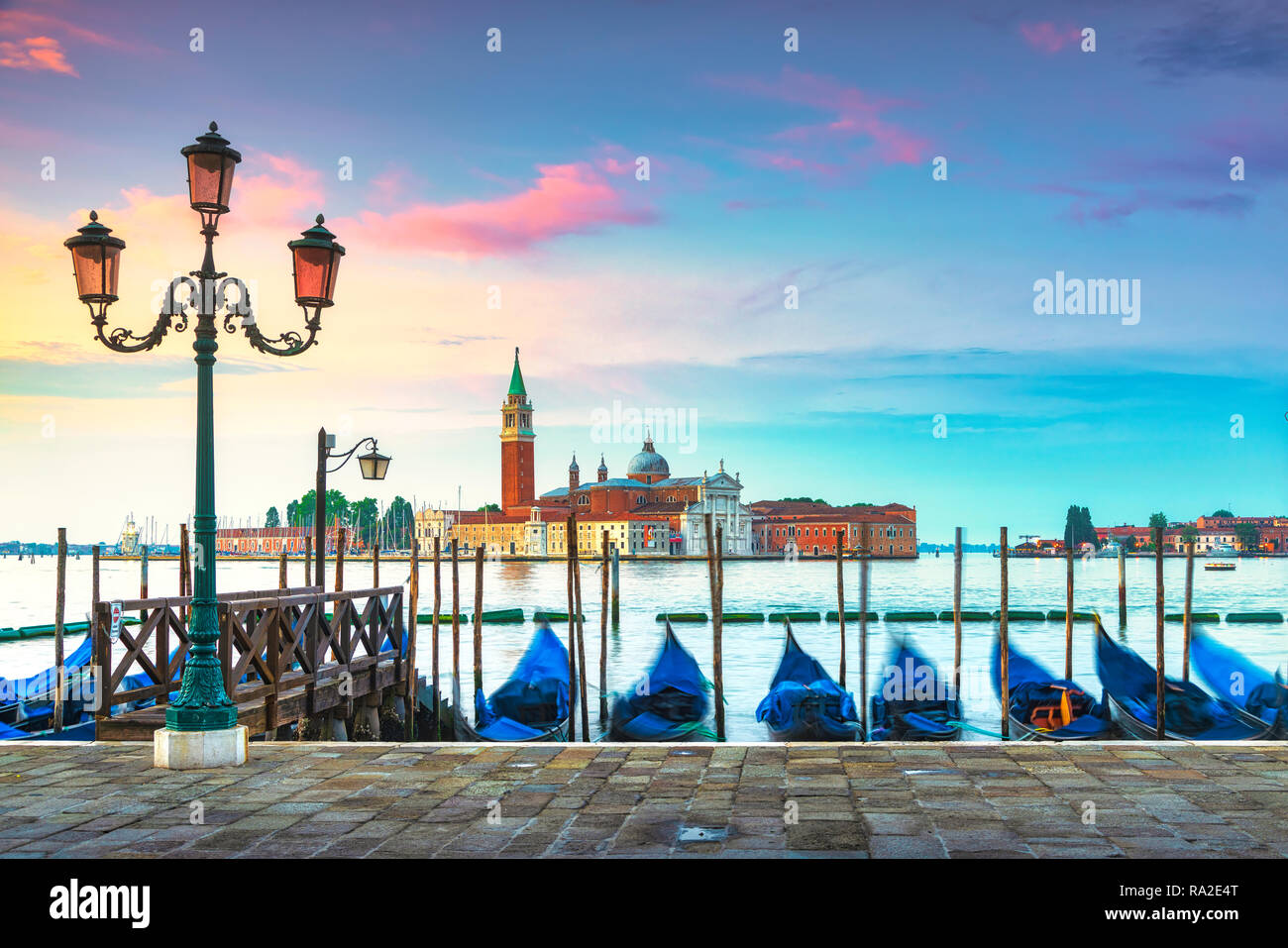 La laguna di Venezia al sunrise, chiesa di San Giorgio Maggiore, le gondole e i poli. L'Italia, l'Europa. Foto Stock