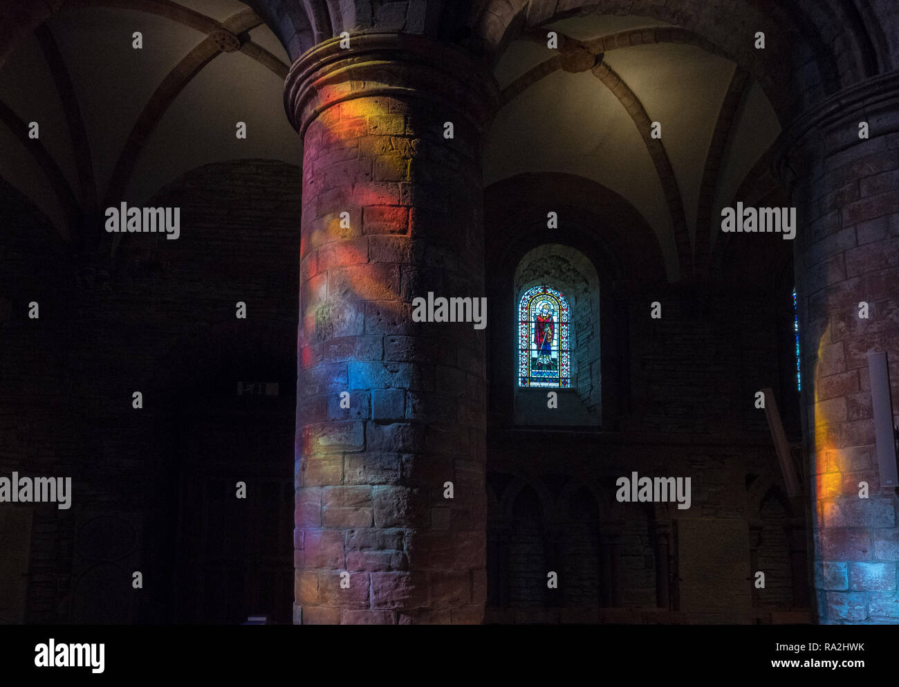 Archi interni di San Magnus Cathedral a Kirkwall sono illuminate da un arcobaleno di luce proveniente attraverso le vetrate della facciata occidentale Foto Stock