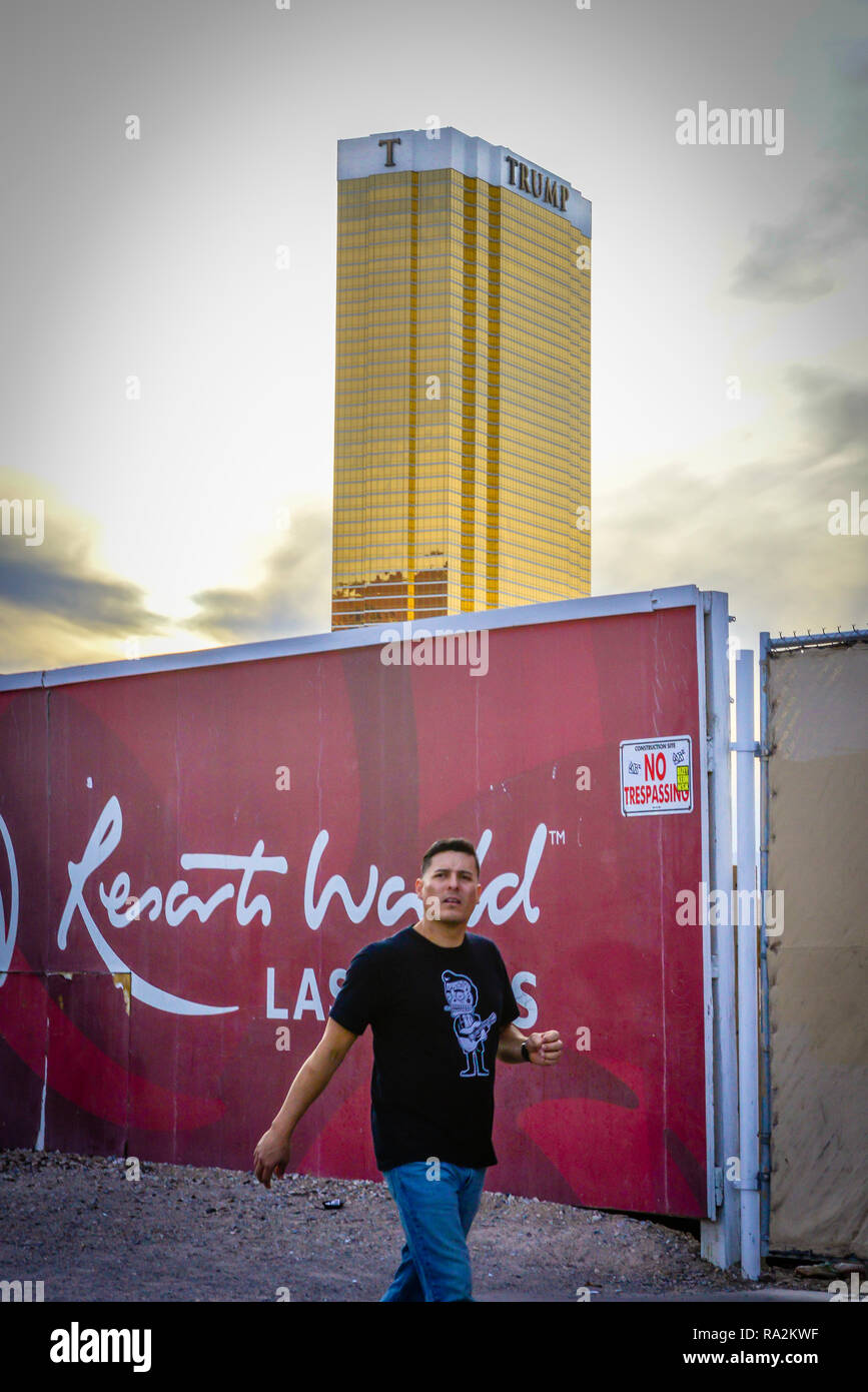 L'uomo con la possibilità di passeggiare lungo la Strip di Las Vegas in prossimità di una zona di costruzione con Trump Hotel e Casino, luccicanti oro al tramonto che si profila in background Foto Stock