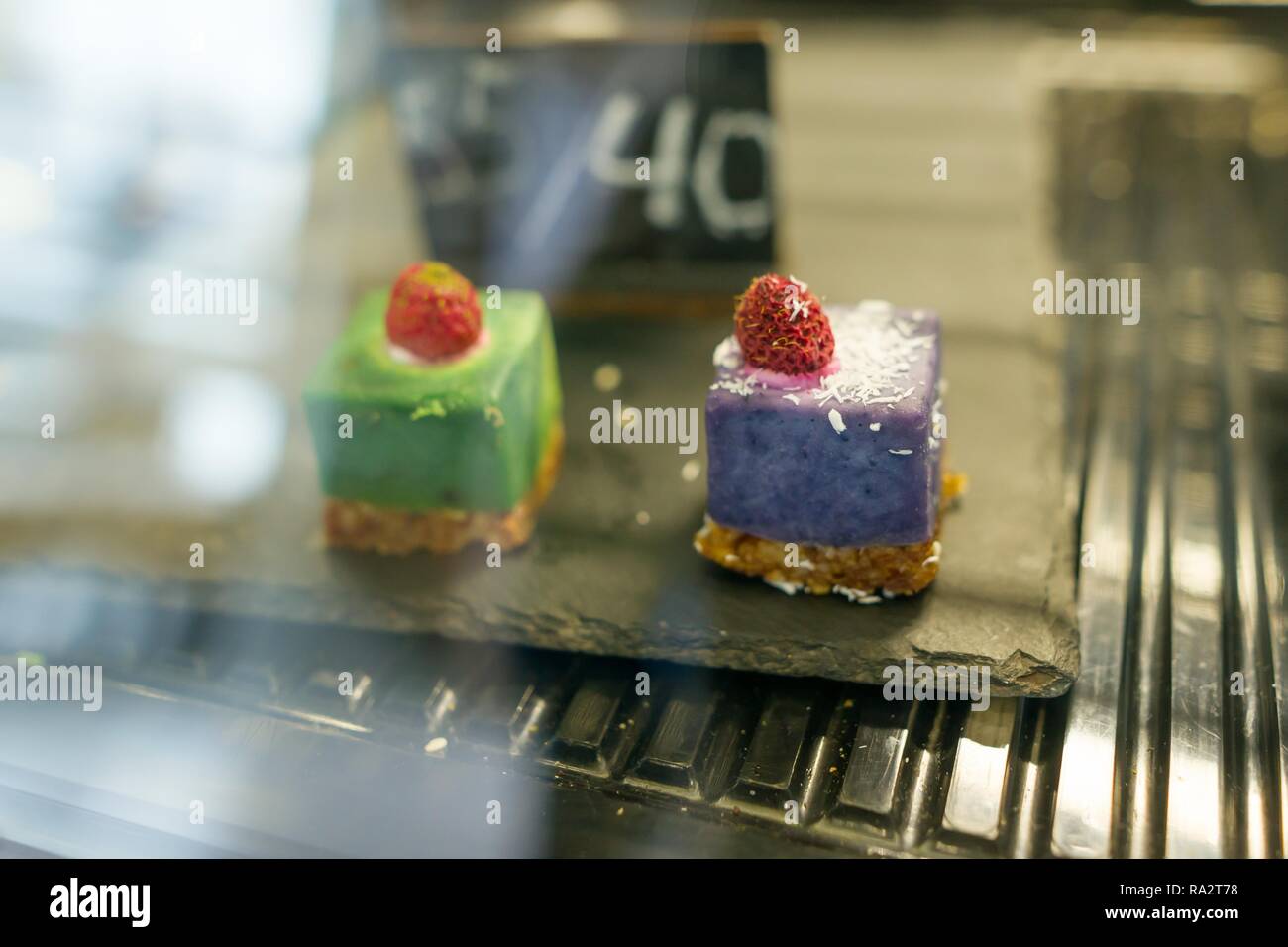 Freschi dolci colorati close-up, in vendita in coffee shop vetrina. Foto Stock