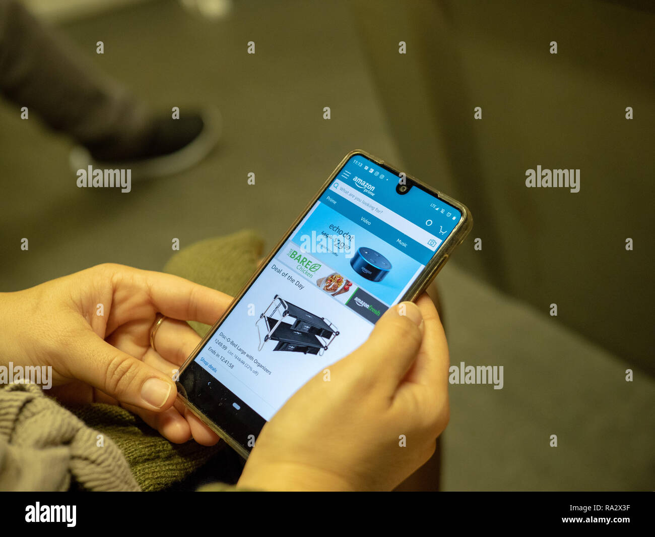 Donna shopping per l'Eco Dot su Amazon mobile app sulla schermata di iPhone mentre il pendolarismo sul treno della metropolitana Foto Stock
