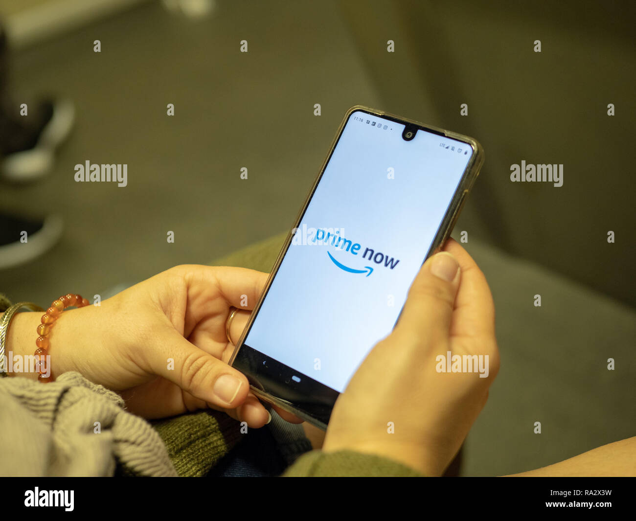 Apertura di donna Amazon ora app su Android lo schermo del dispositivo durante gli spostamenti sul treno della metropolitana Foto Stock